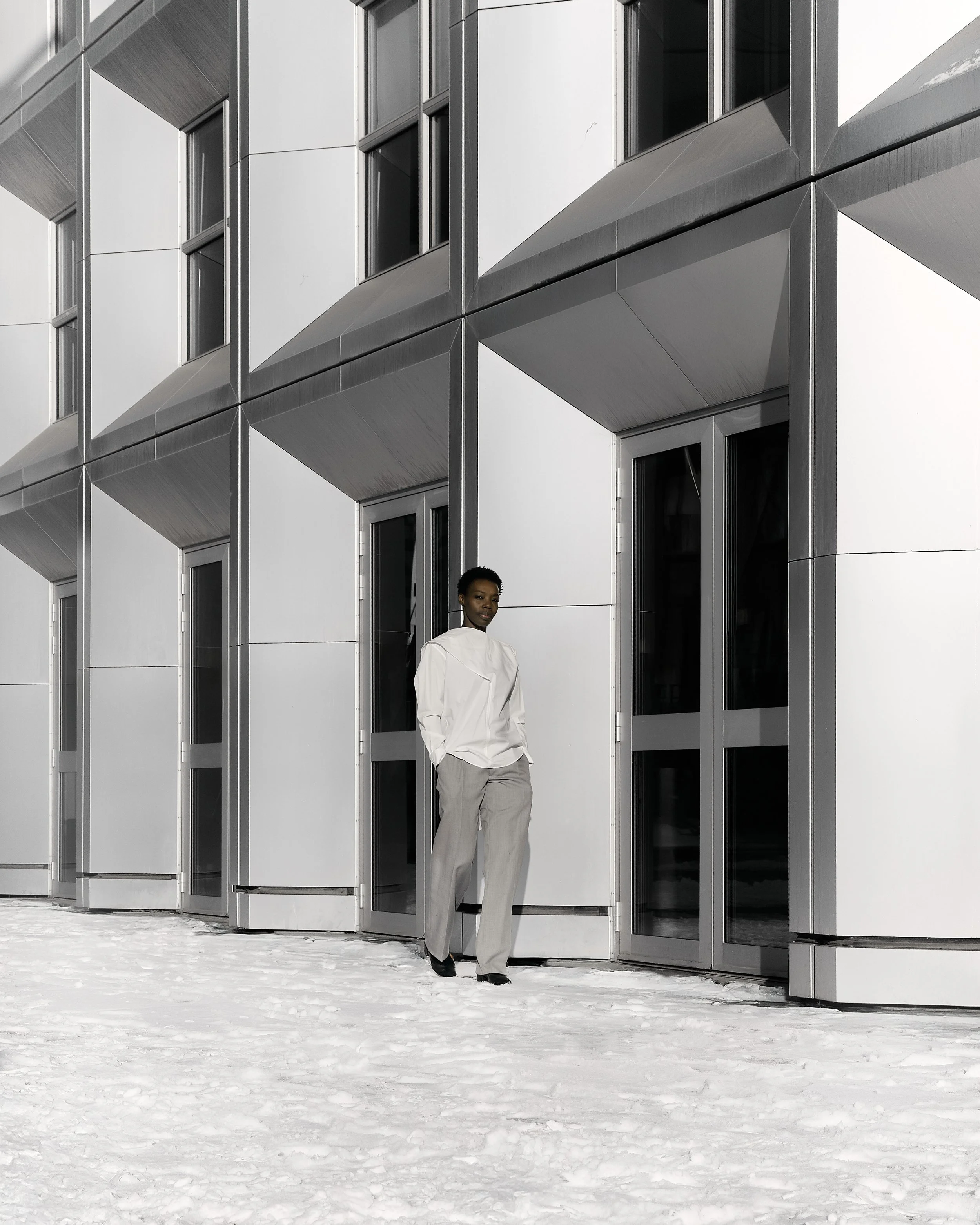 A woman standing outside a modern building with a snow-covered ground.