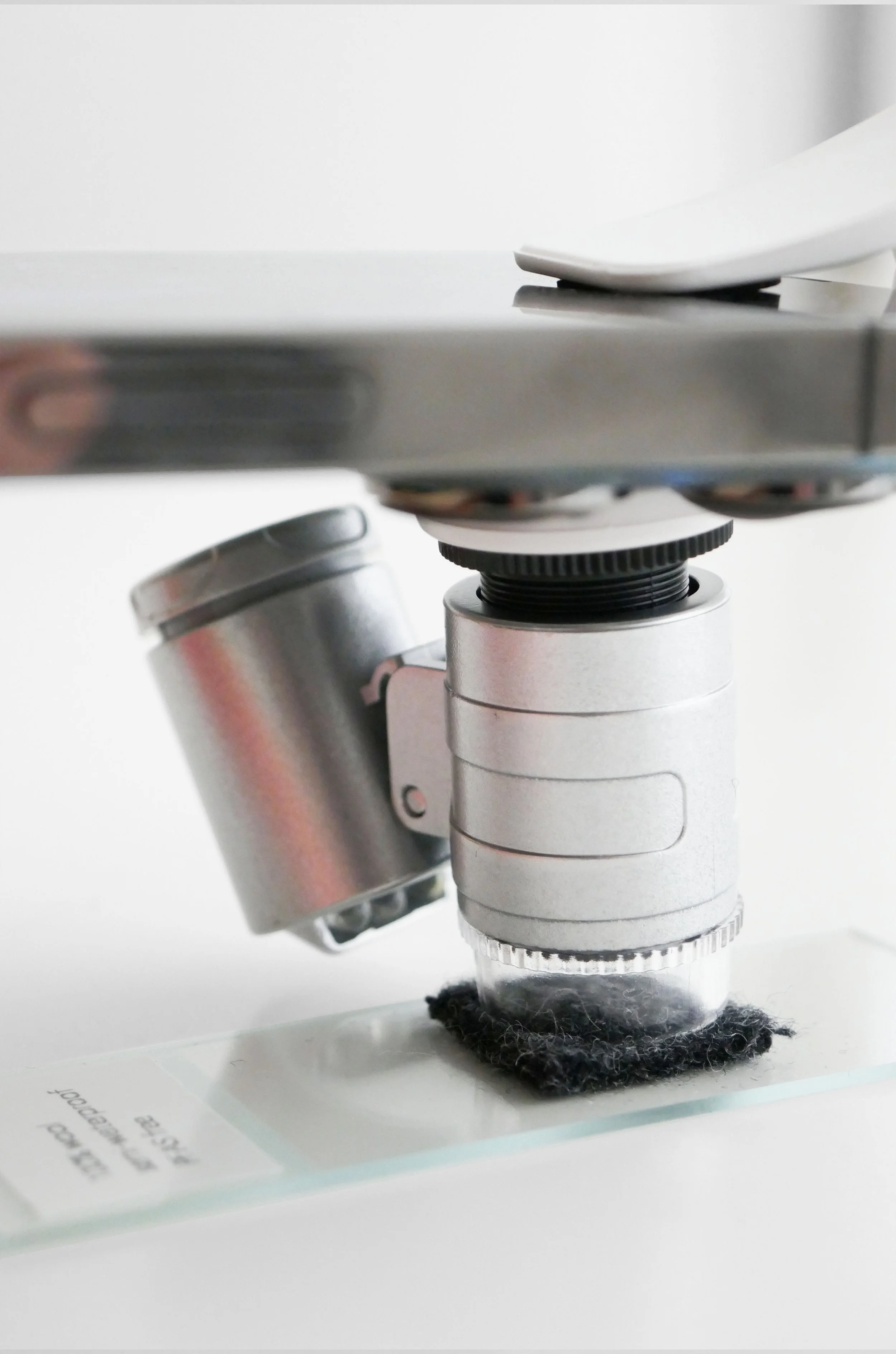 Close-up of a microscope examining a sample on a glass slide.