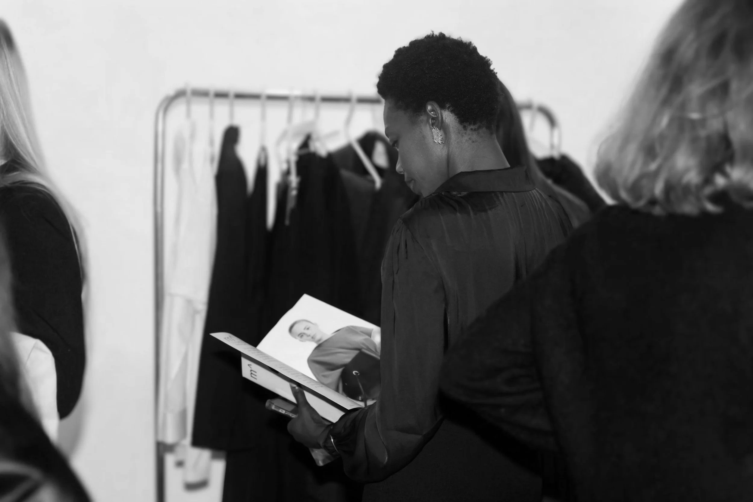 Black woman with short hair looking at a magazine in a clothing store.