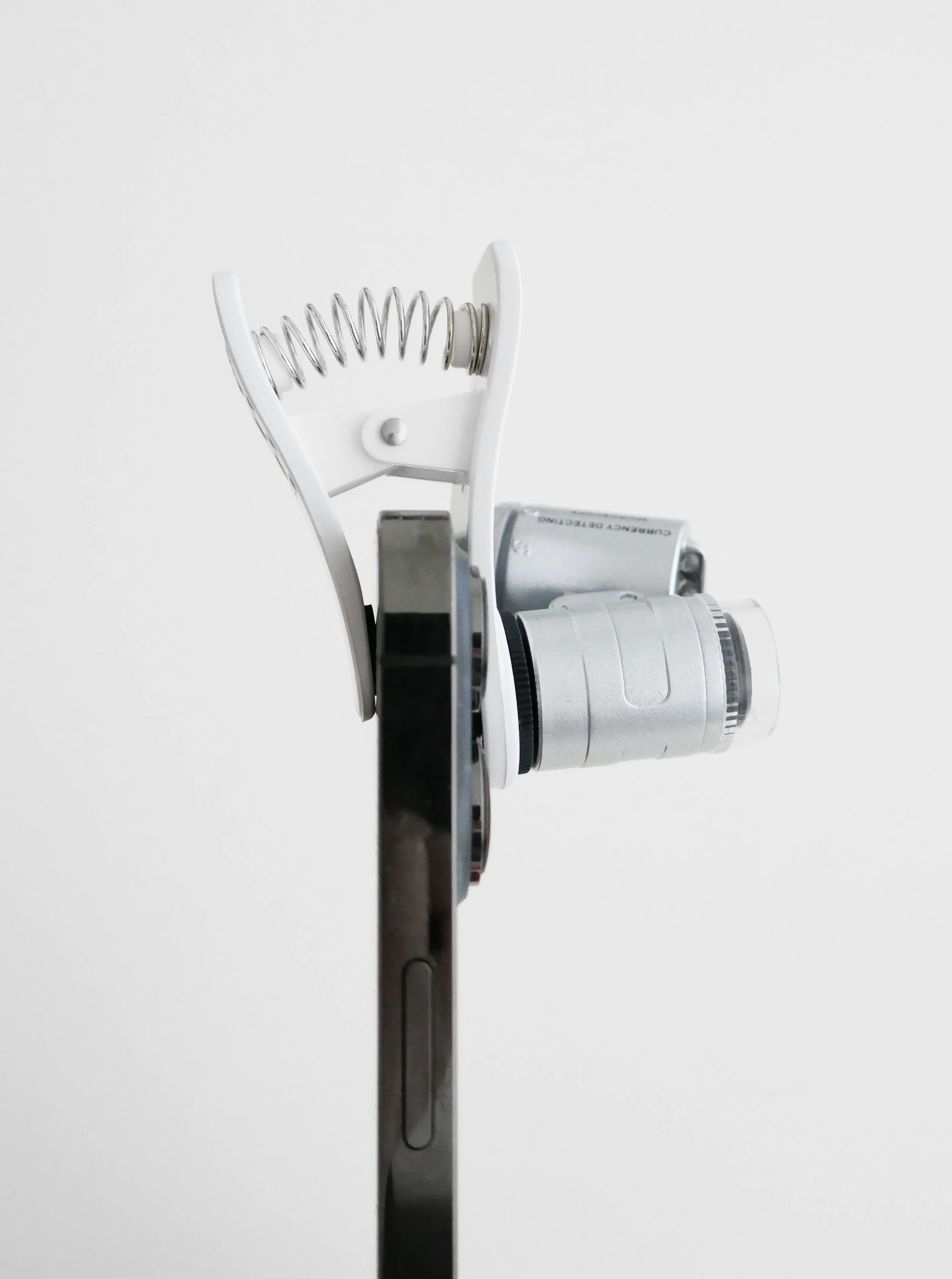 Close-up of a microscope viewed from the side against a plain white background.