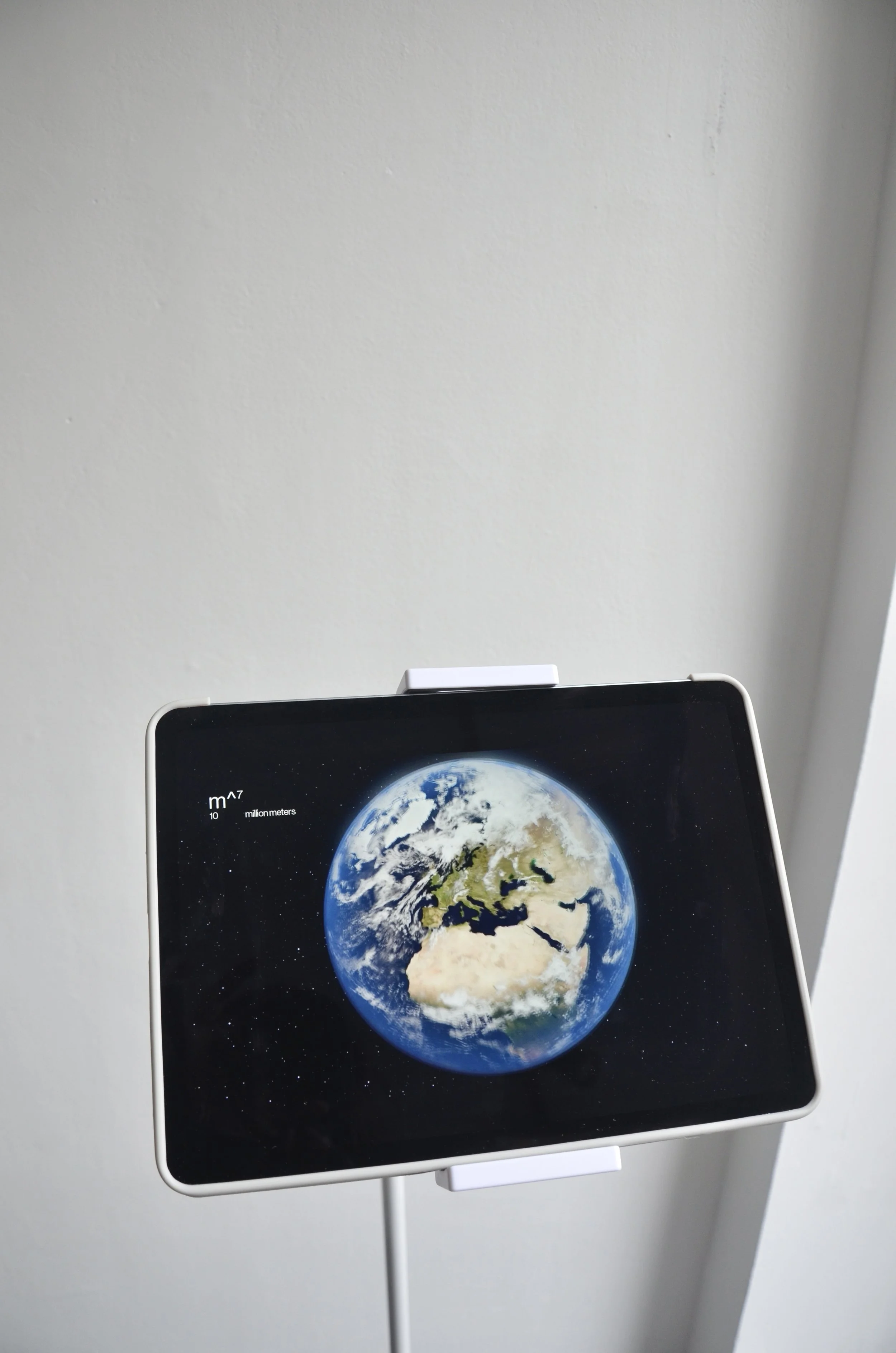 A digital display showing Earth from space, with a scale of meters on the left side. m^ ready to wear showroom.