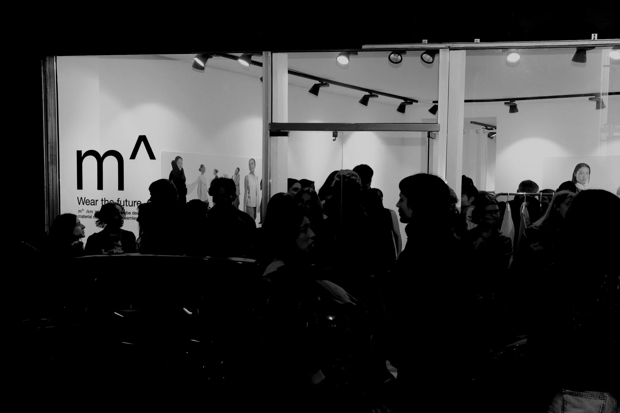 Arowd of people inside a store with clothing displays and a sign that reads 'm^ Wear the future'. We celebrated the launch of m^ — the beginning of a journey where design meets science and innovation. A ready-to-wear elegant, technical brand.