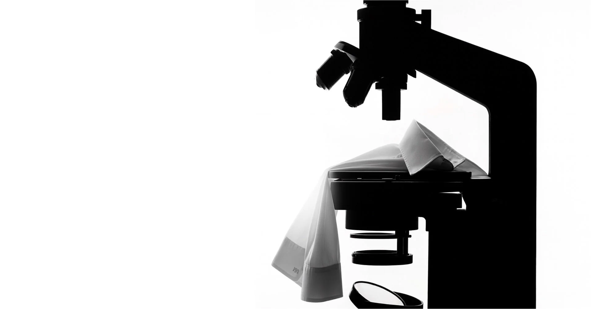 Silhouette of a microscope, a mpower non iron shirt against a white background.