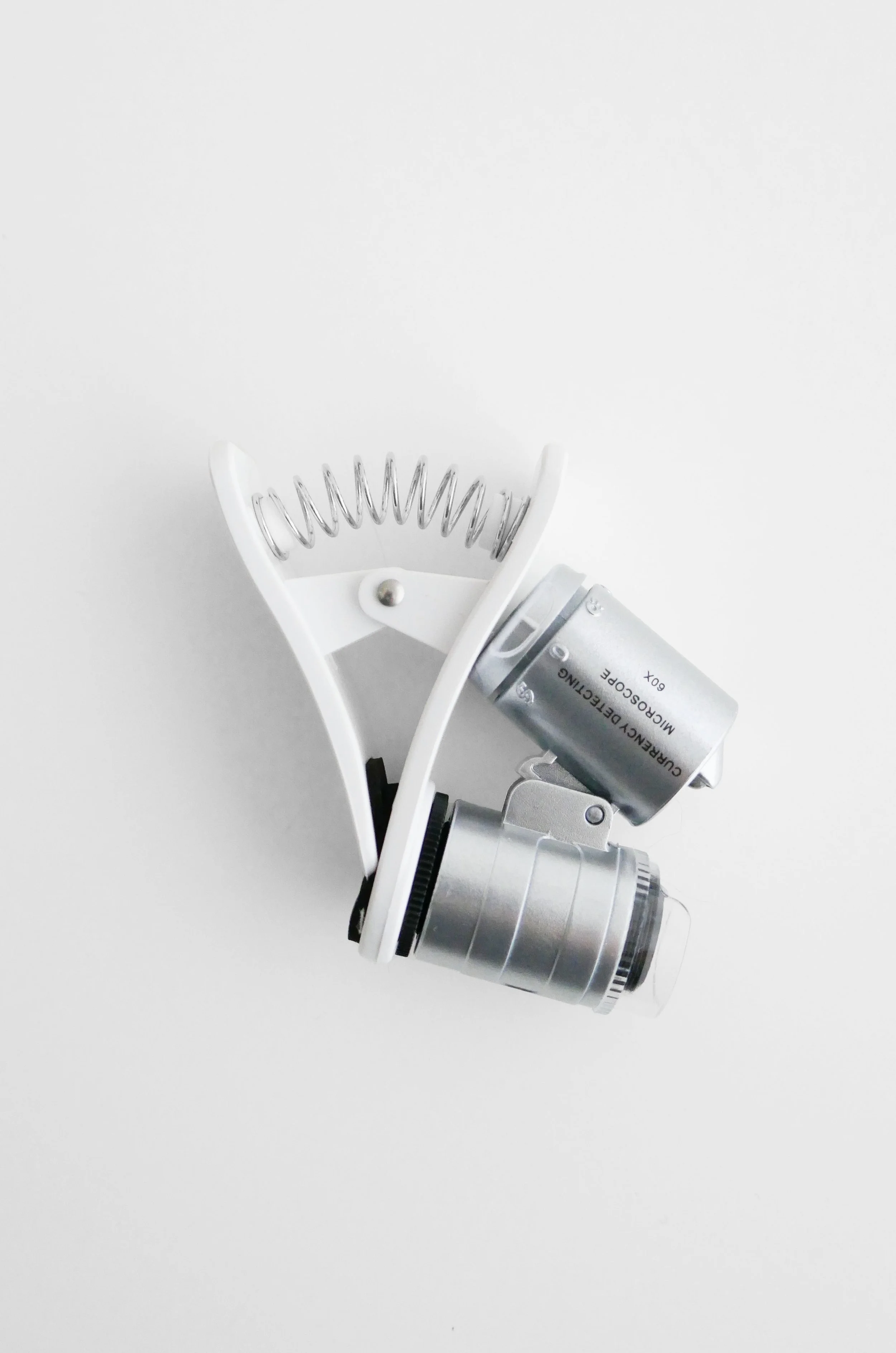 A microscope with a white handle and a silver body, placed on a white background.