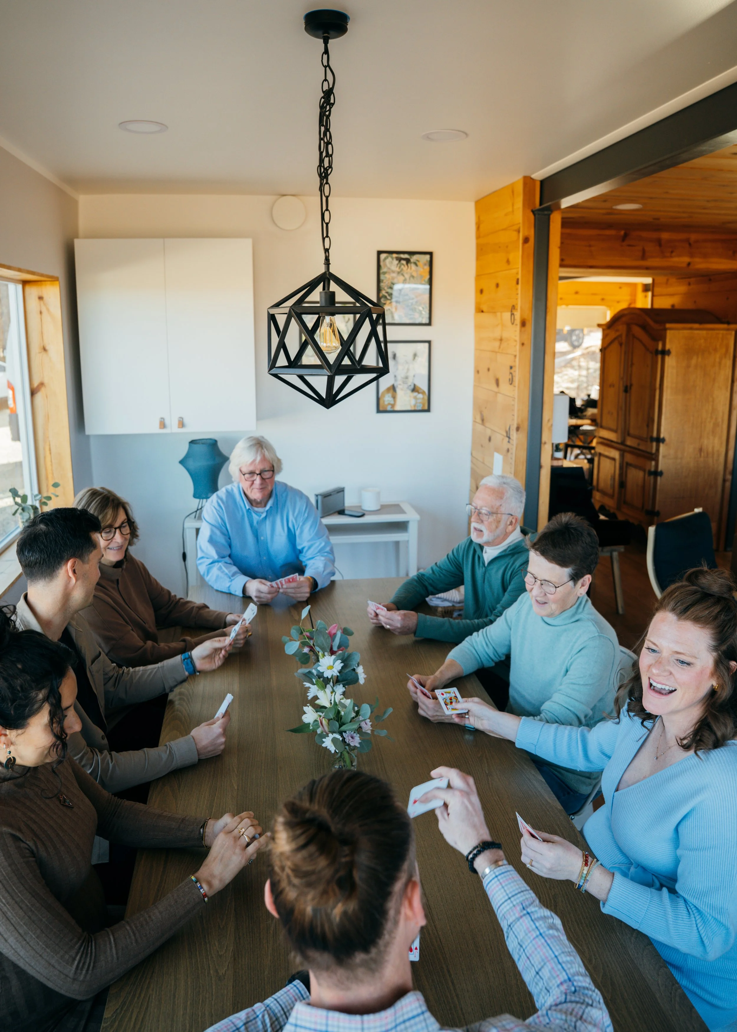 Extended family gathered around a dining table playing cards during a cozy indoor winter photo session in Colorado Springs