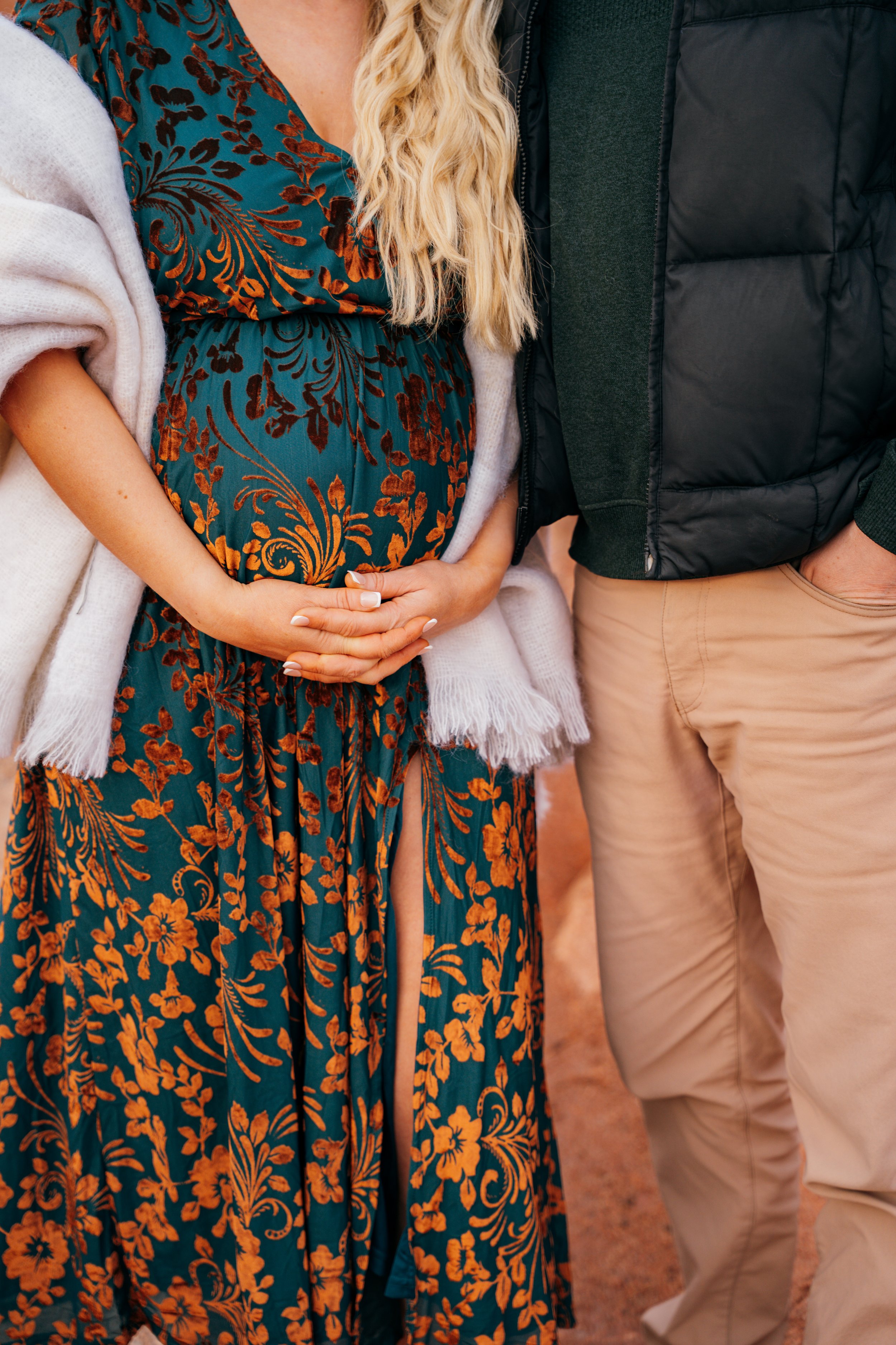 Close-up maternity detail during an outdoor winter session in Colorado Springs with warm textures and red rock tones