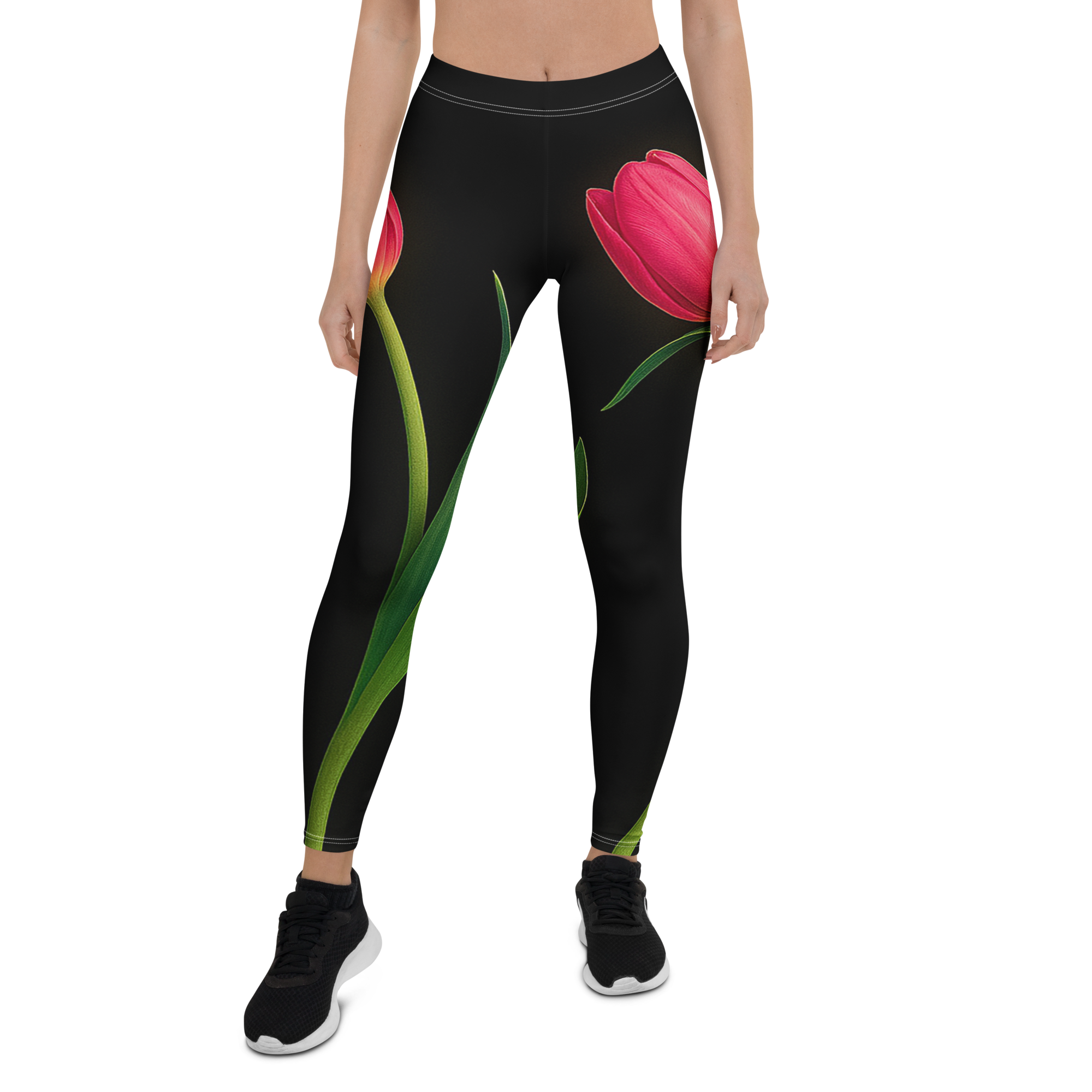 Leggings with a large red tulip design worn by a woman, paired with black sneakers with white soles, standing beside a beige background.