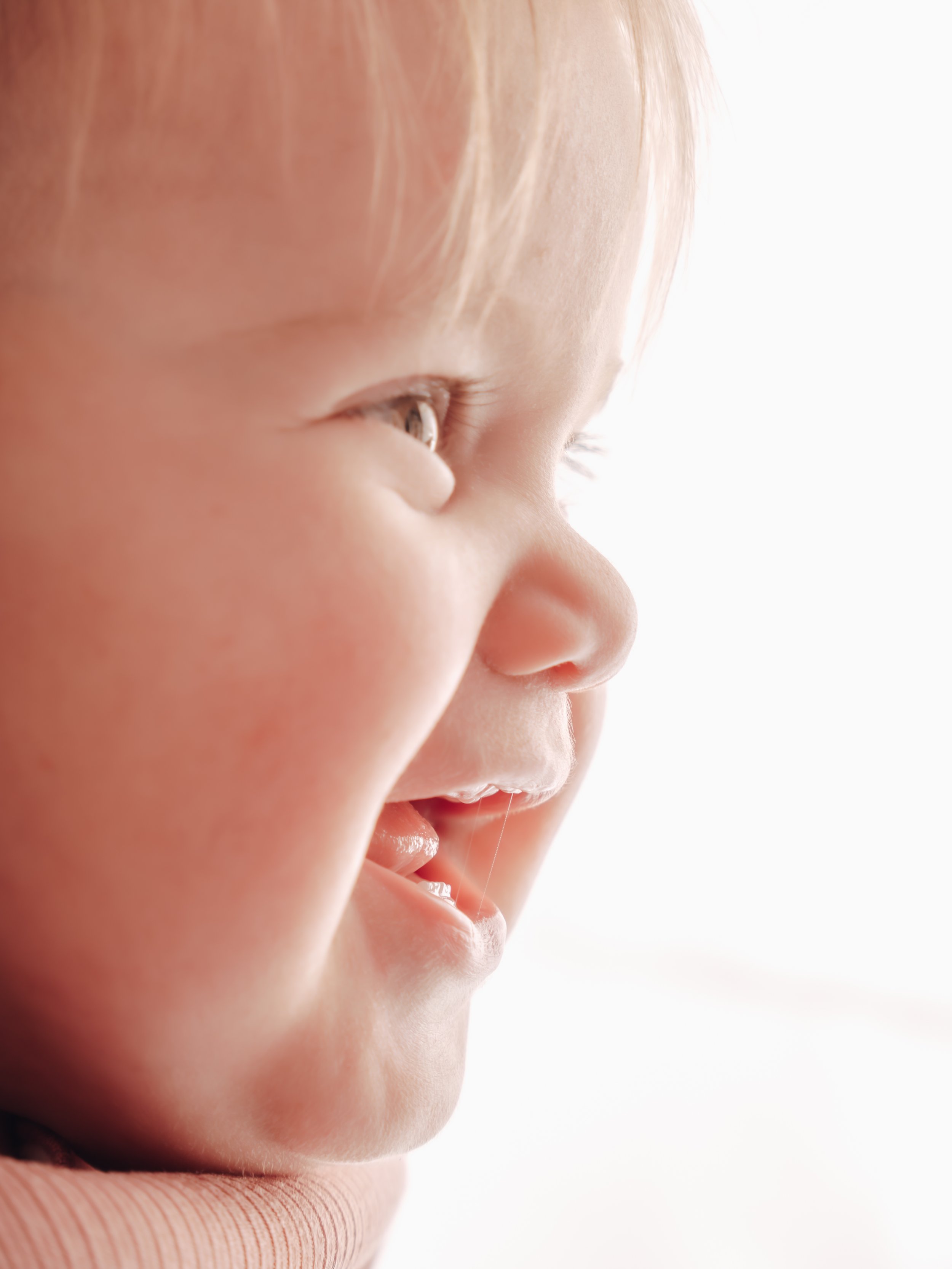 Close-up of a young child's smiling face in profile with soft lighting.