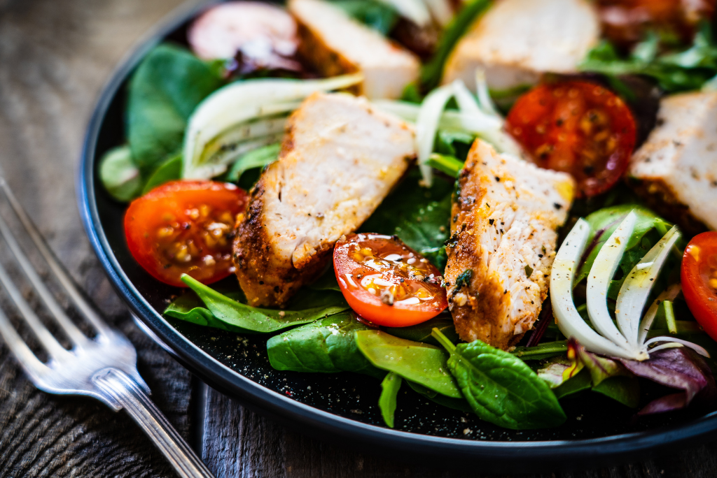 Fresh salad with grilled chicken, cherry tomatoes, sliced onions, and mixed greens