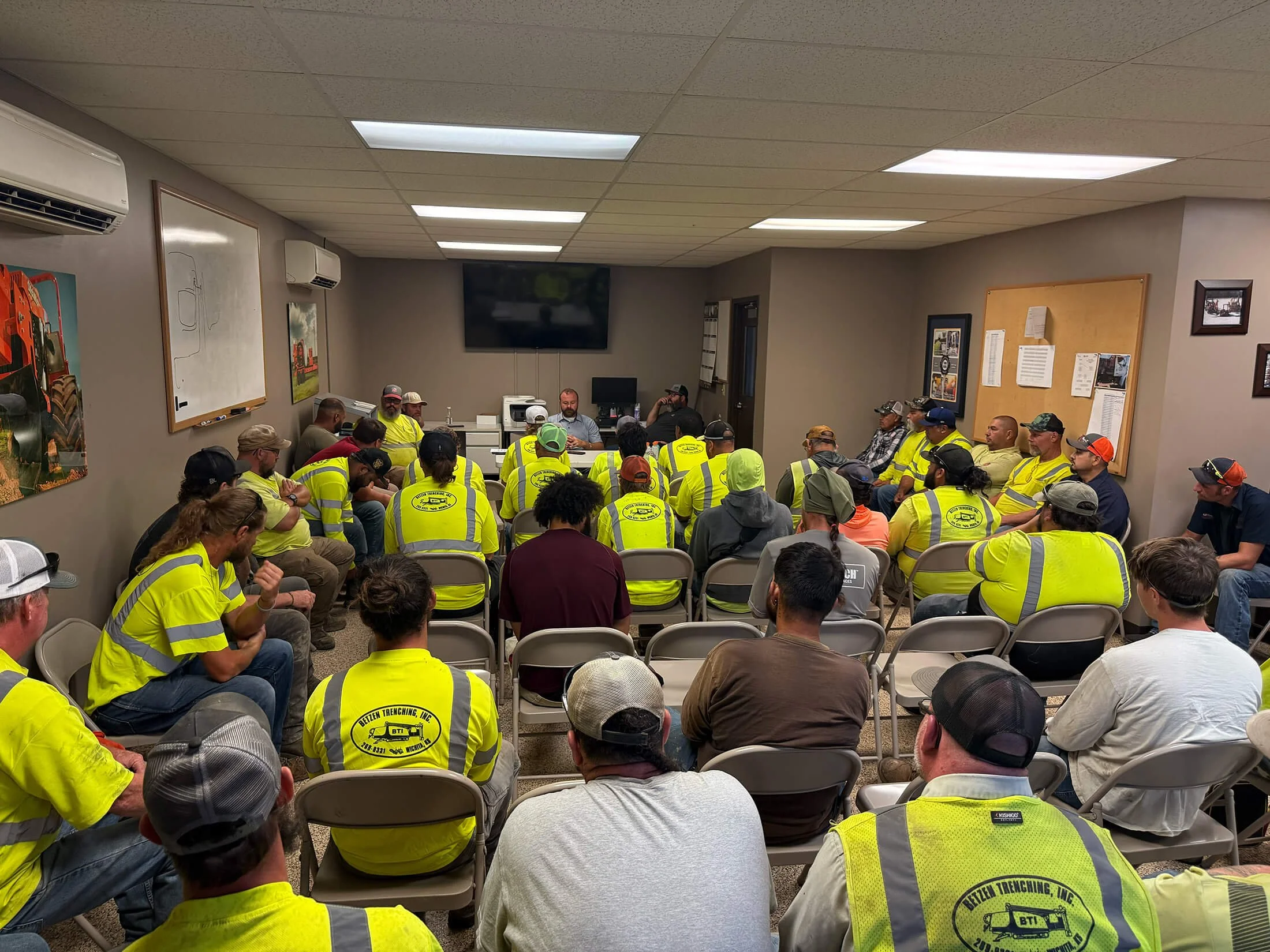 Group of people in high-visibility yellow shirts attending a meeting in a conference room.