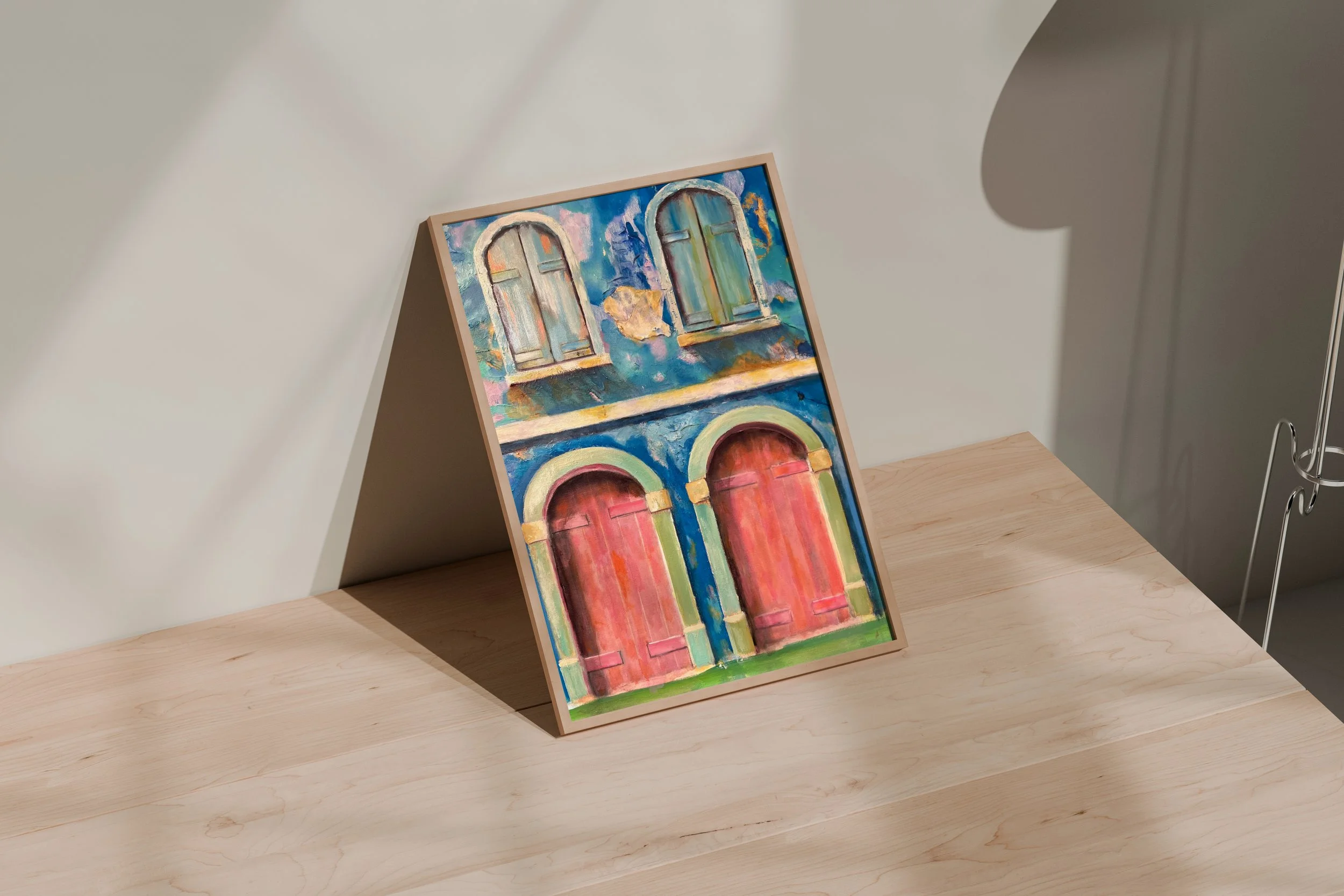 Colorful painting with four arched windows, two in pastel green and two in red, displayed on a wooden surface in a room with neutral walls.