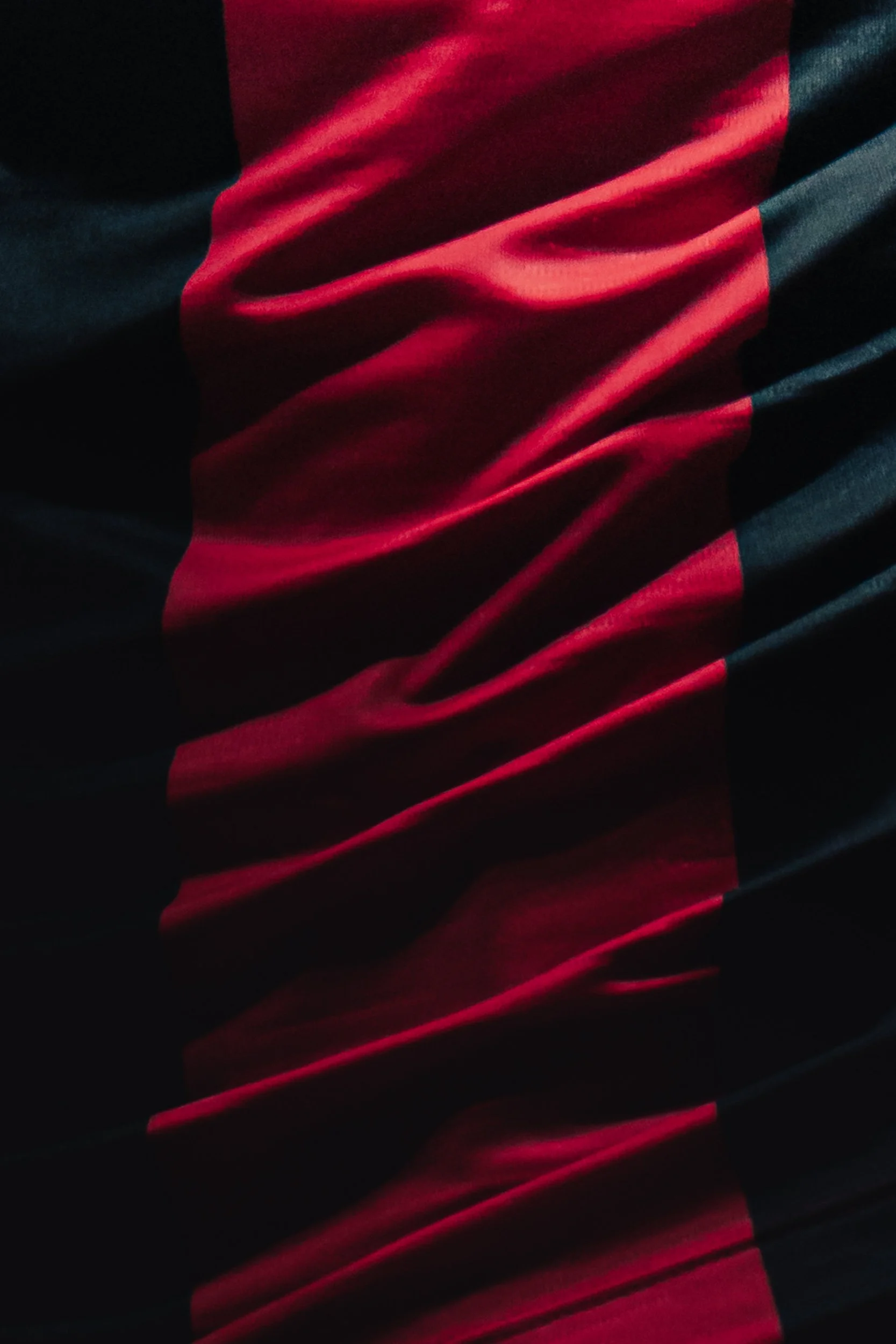 Tissu en tissu fluide avec rayures rouges et noires, plié en surface avec des plis visibles.