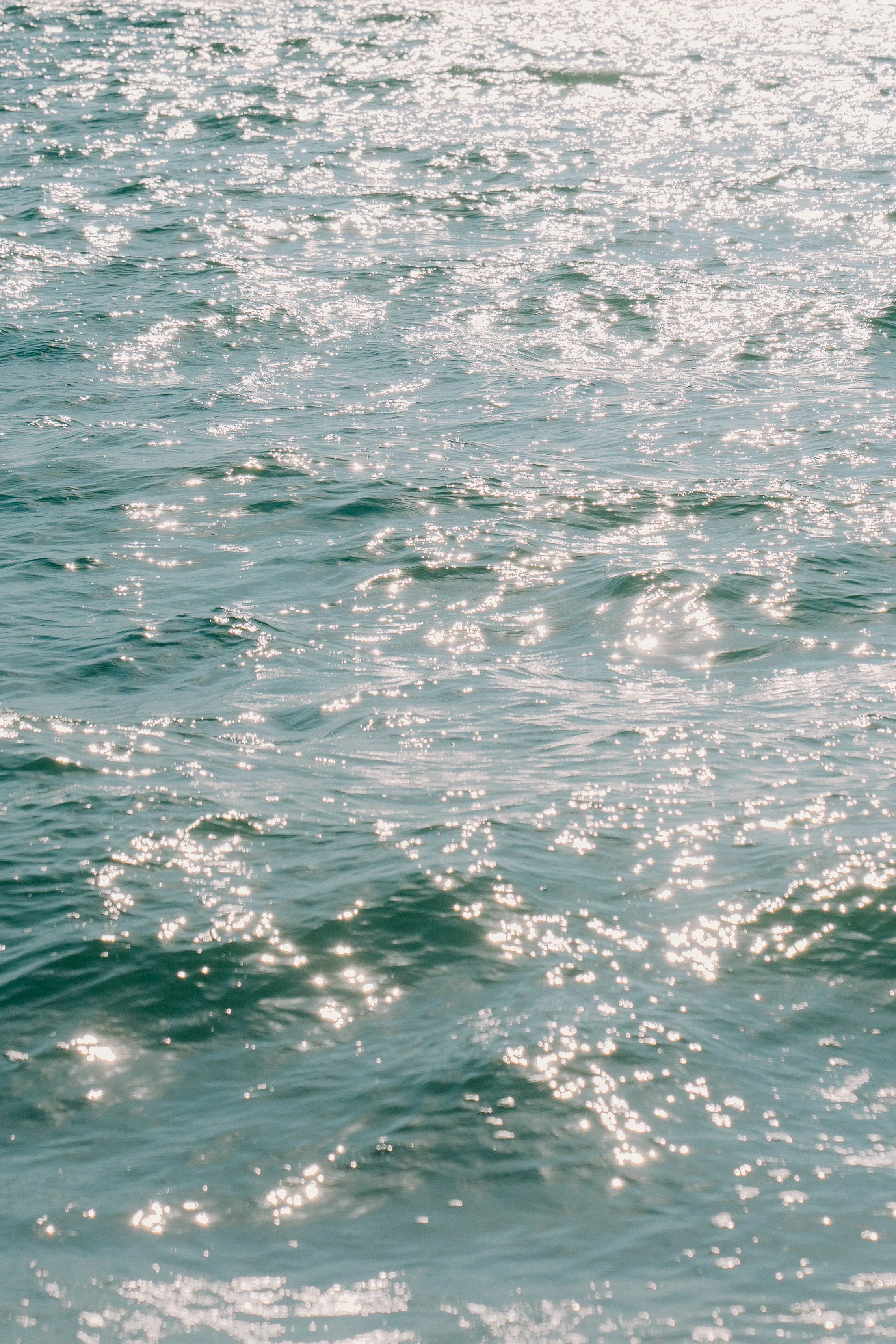 Sunlit ocean water with gentle waves and reflections of sunlight.