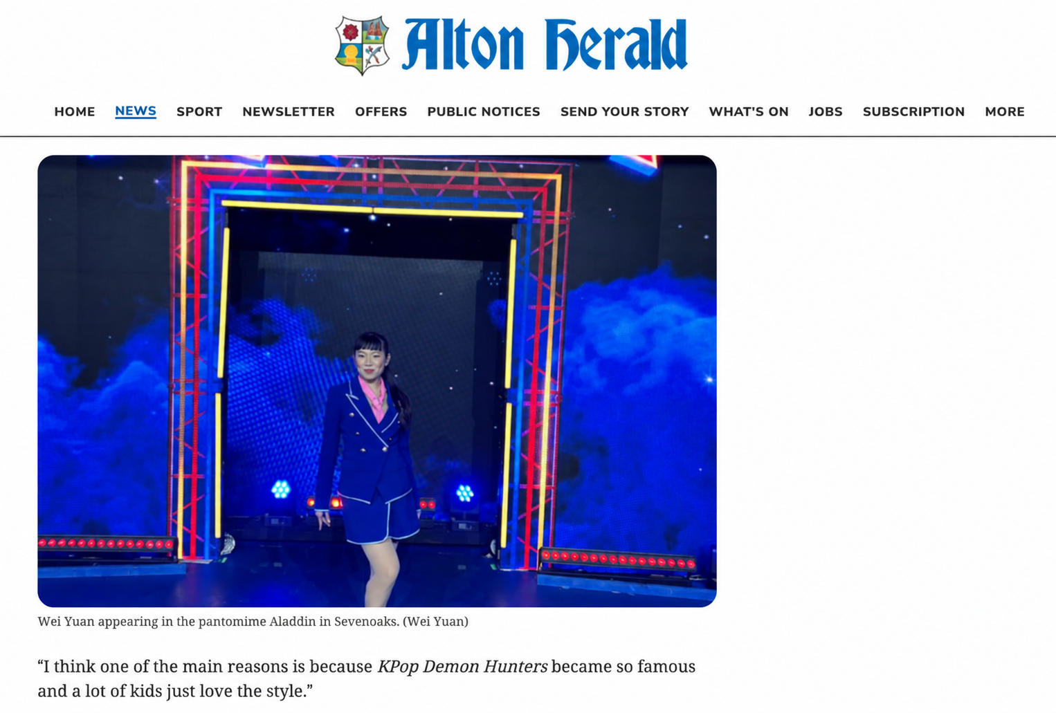 Wei Yuan appearing in a stage performance of Aladdin in Sevenoaks, wearing a blue costume, standing in front of a colorful illuminated entrance with smoke and blue lighting effects.