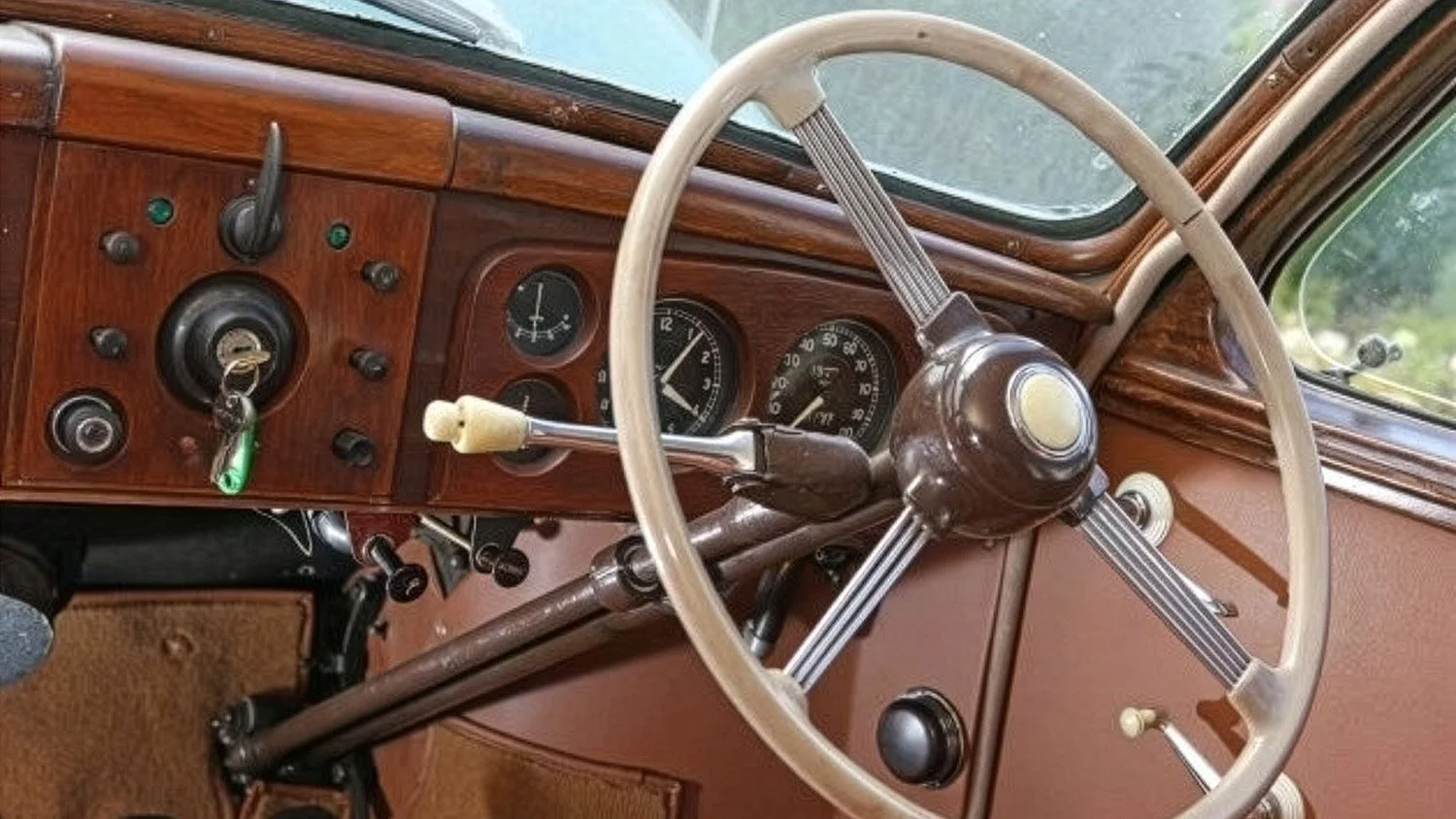 Interior of a vintage car showing the dashboard, steering wheel, and ignition key with a green keychain.