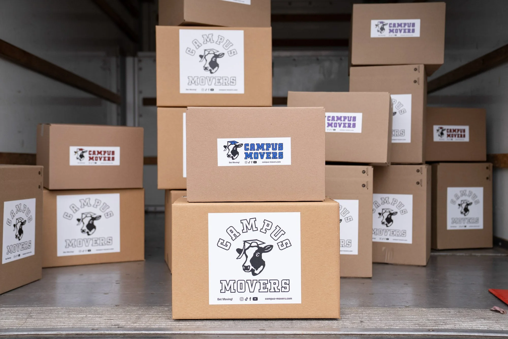Boxes with 'Campus Movers' labels arranged in a storage area or truck.