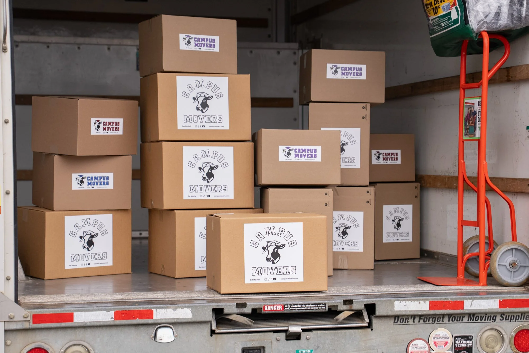 Cardboard boxes with stickers reading 'Campus Movers' inside a moving truck.