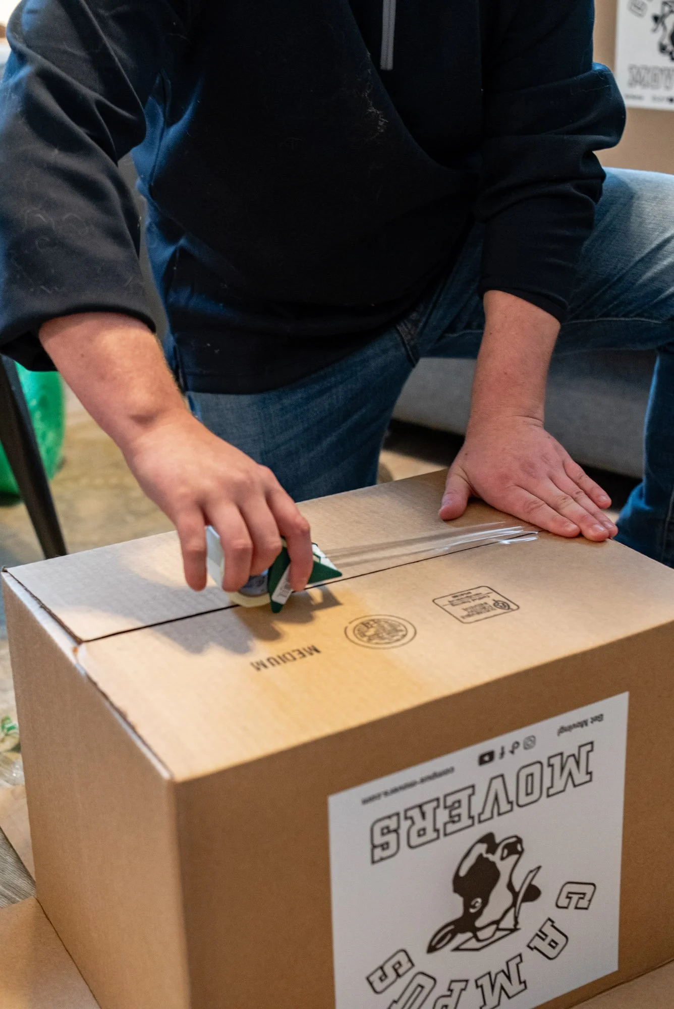 Person sealing a cardboard box with clear packing tape.