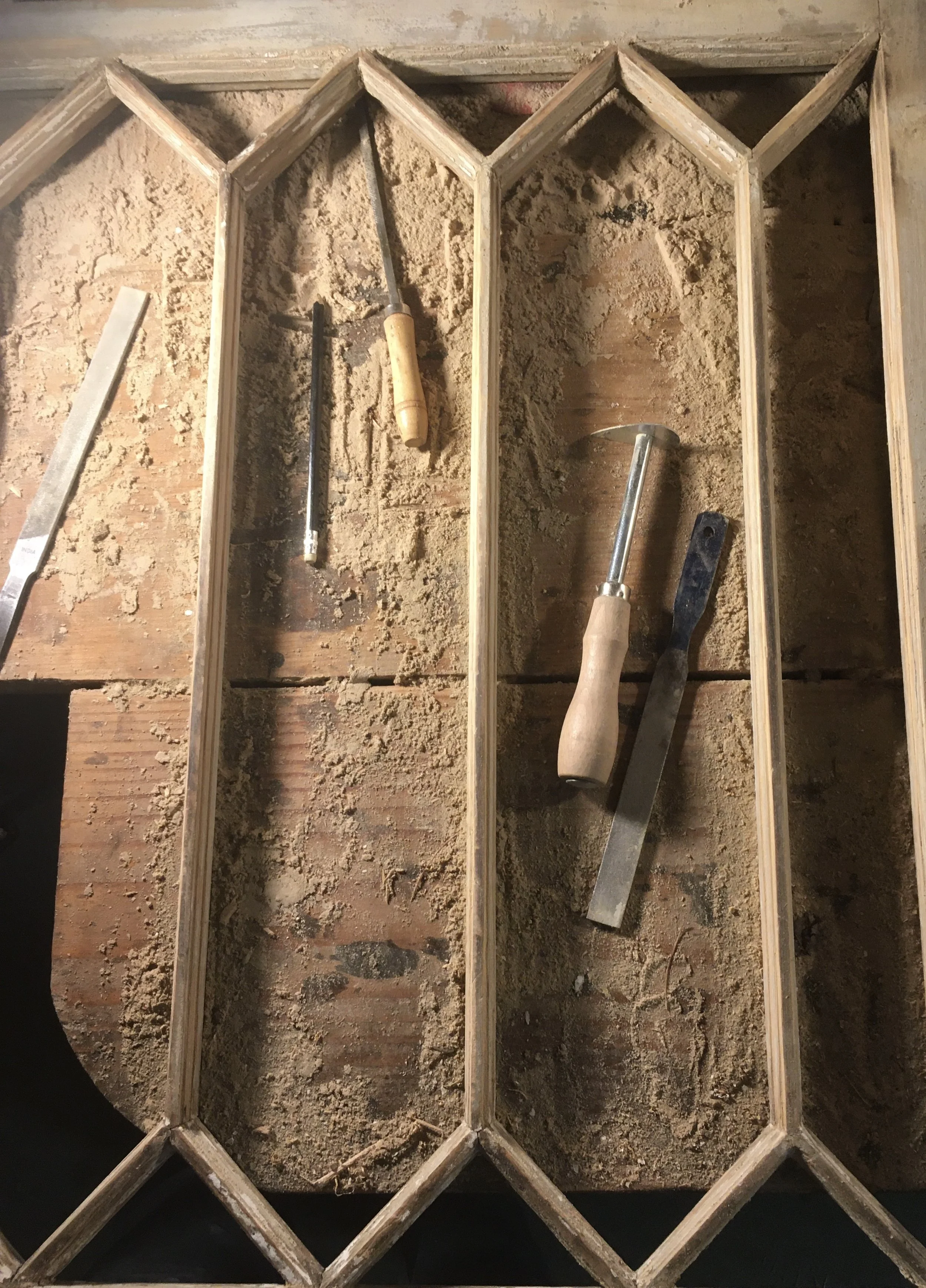 Wooden frame being built with tools such as a chisel, saw, and flat chisel on a work surface.