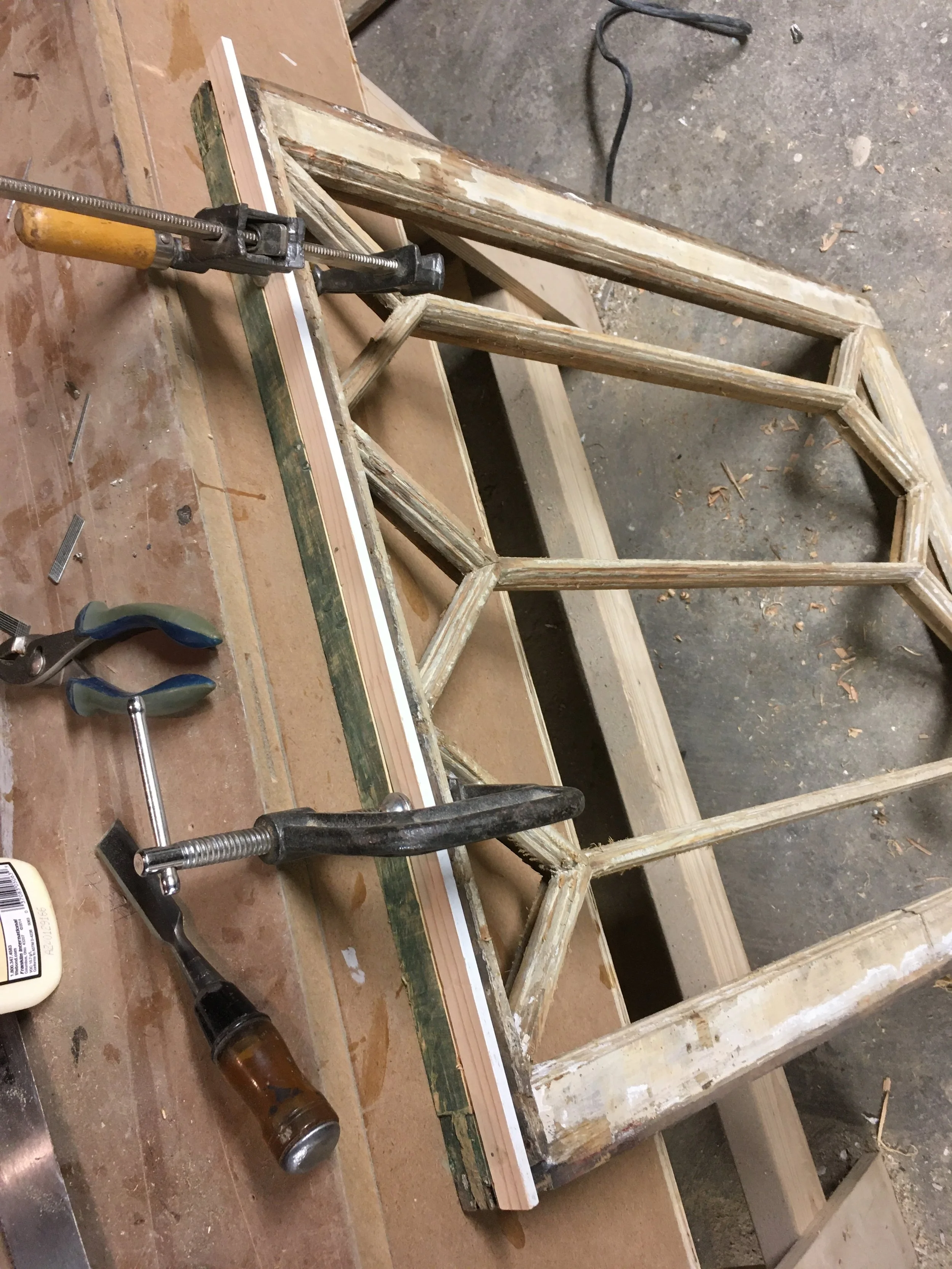 Wooden furniture being repaired or built, with clamps and tools on a workbench.