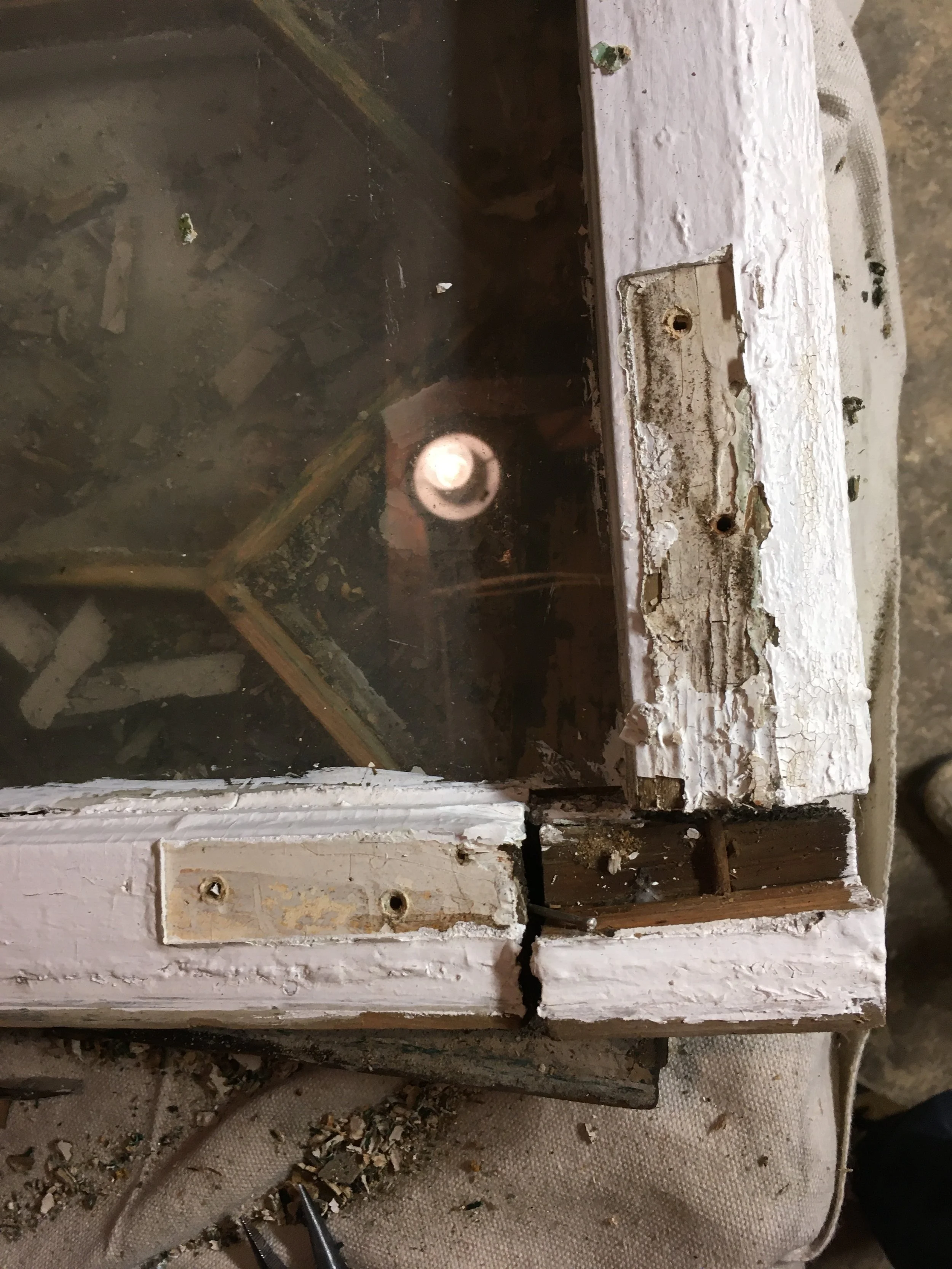 Close-up of a damaged, old wooden and glass display case with peeling paint and broken parts.