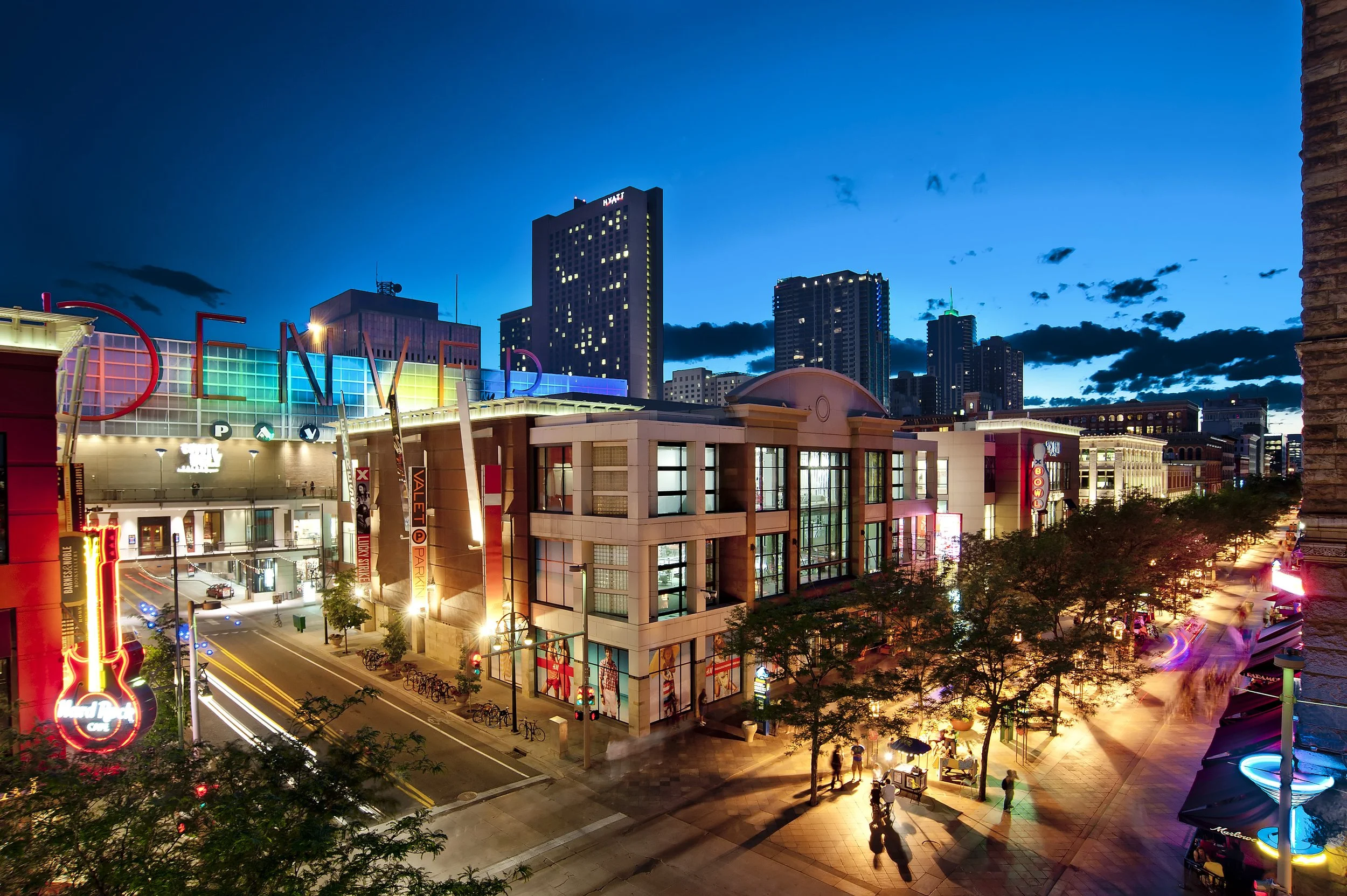 Night view of Downtown Las Vegas with illuminated casinos, hotels, and neon signs, featuring the Fremont Street Experience area with colorful lights and pedestrian traffic.