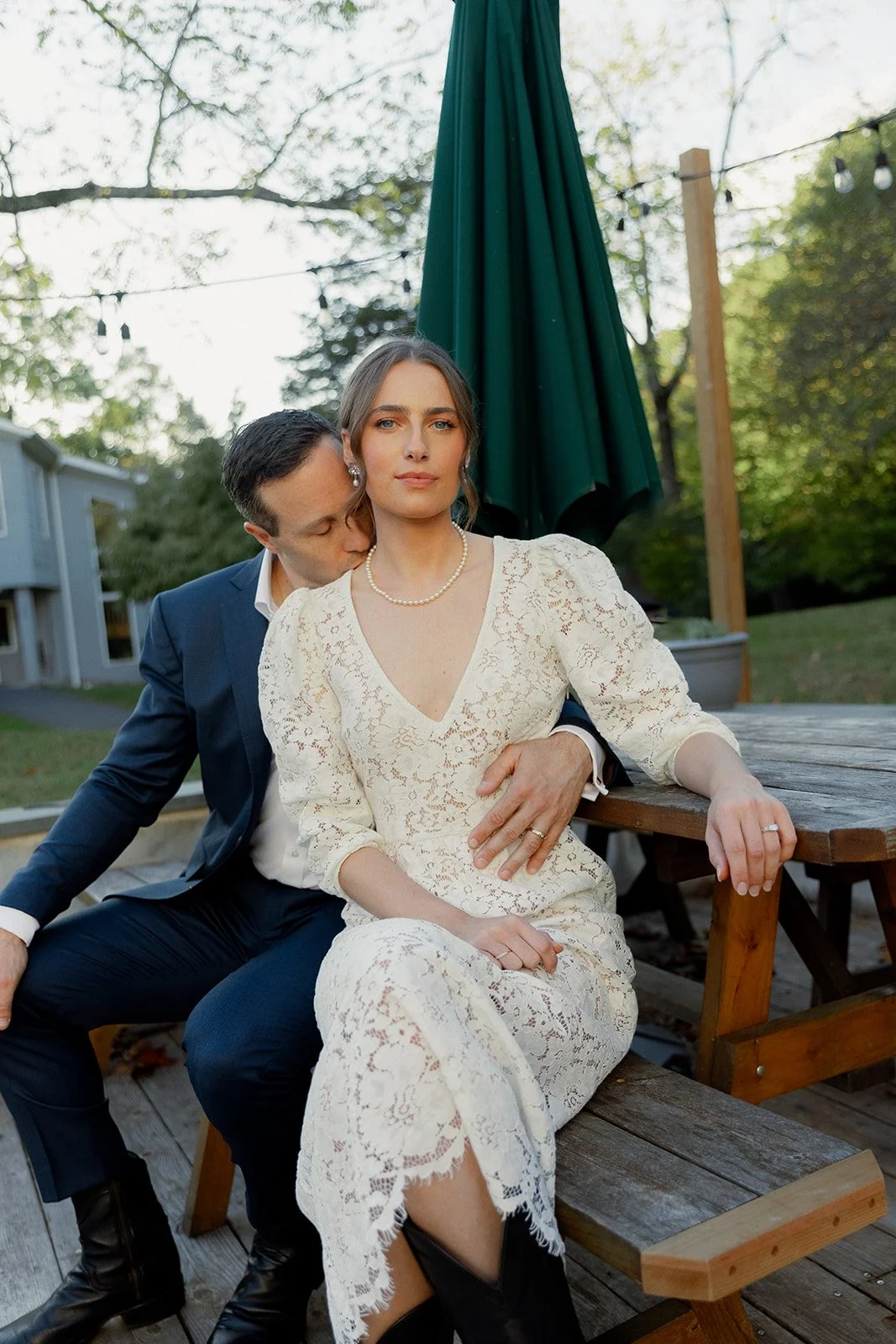 Groom kisses bride in lace dress at intimate outdoor elopement