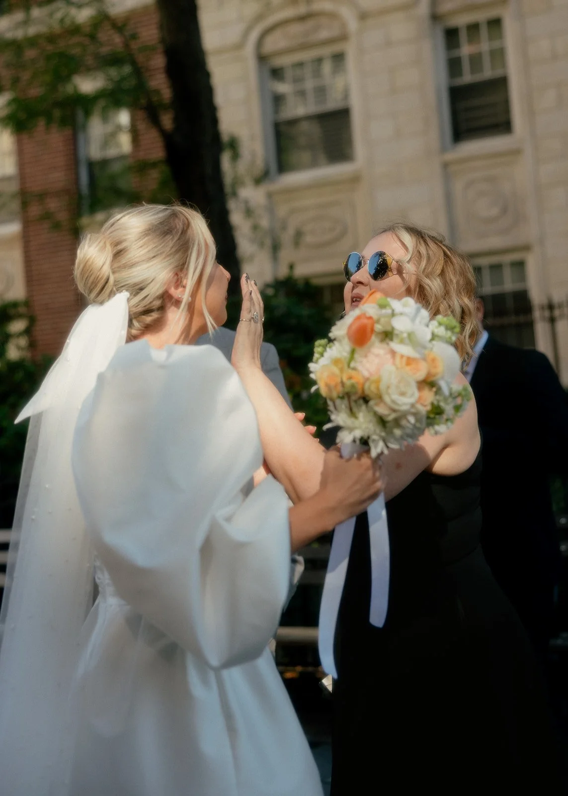 Bride greeting guest with bouquet, NYC wedding day