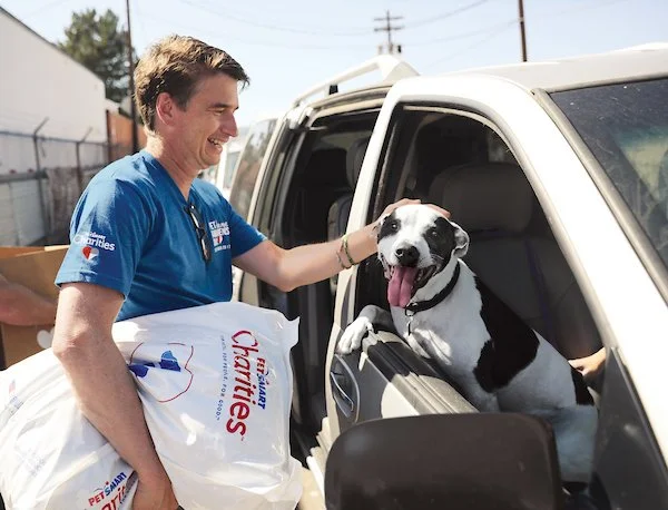 PetSmart Charities Volunteer petting a dog in a car.