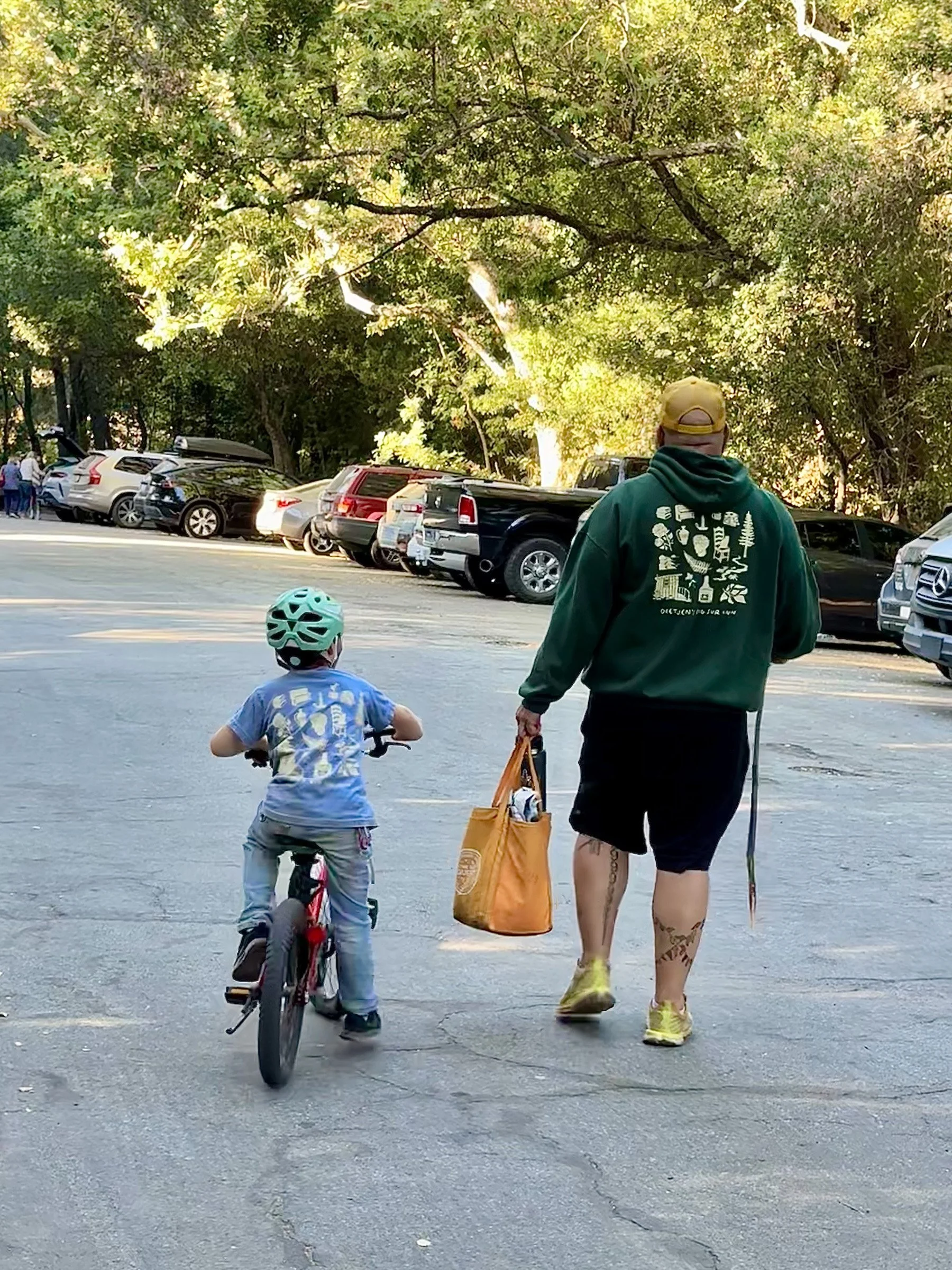  A man walking with a small boy next to him on a bike 