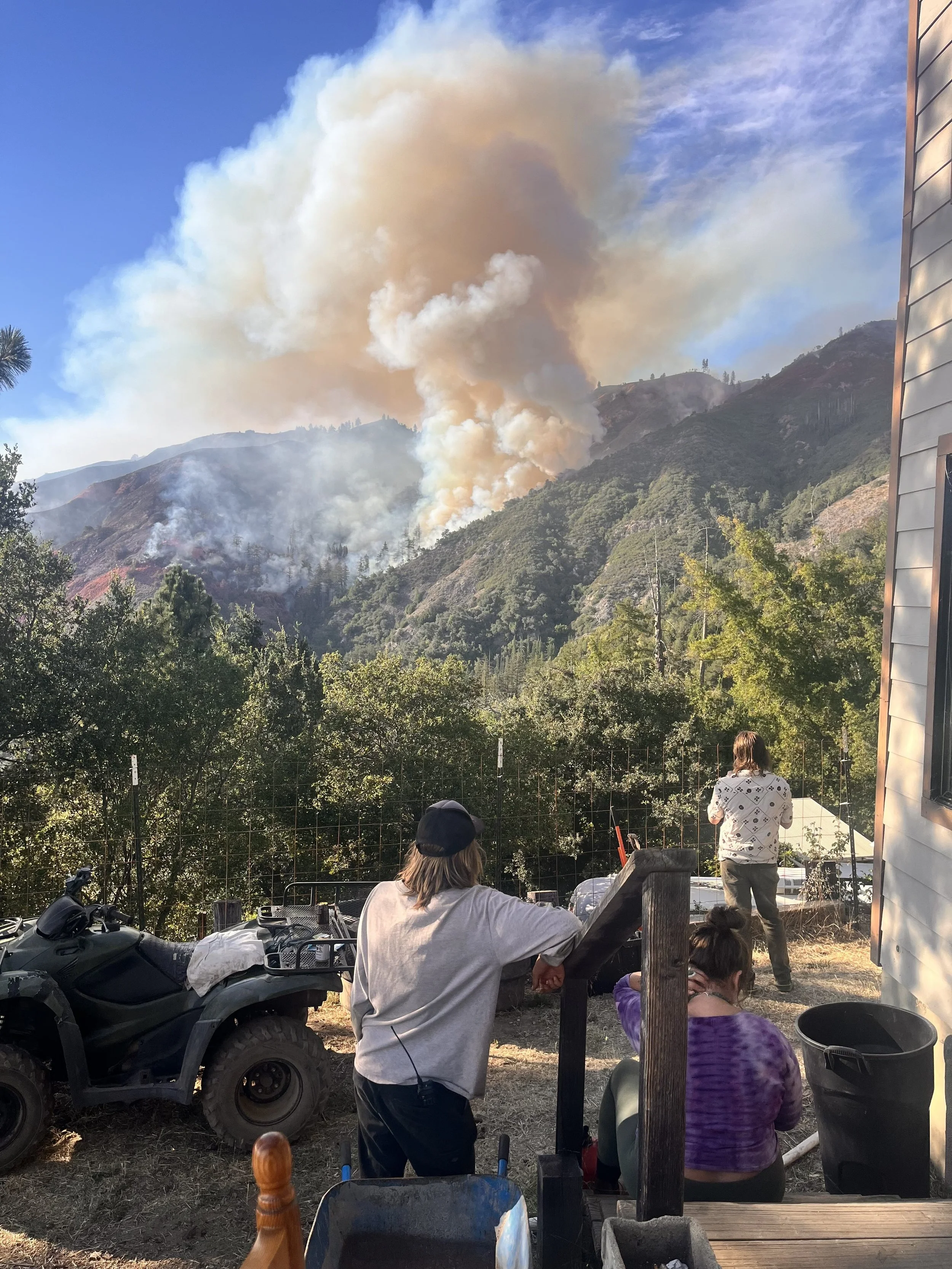 People watching large plume of smoke on a mountain ridge