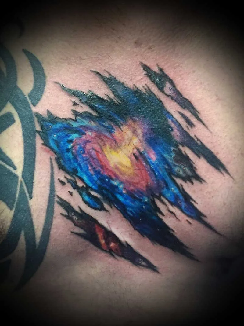 Colorful tattoo of a galaxy or nebula on skin with jagged black streaks around it.