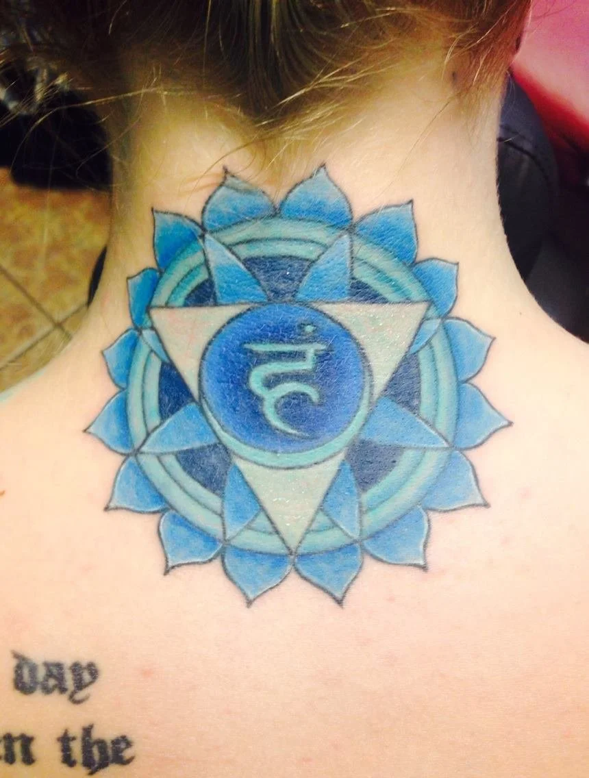 Tattoo on neck featuring a blue lotus flower with a blue energy symbol and geometric shapes.
