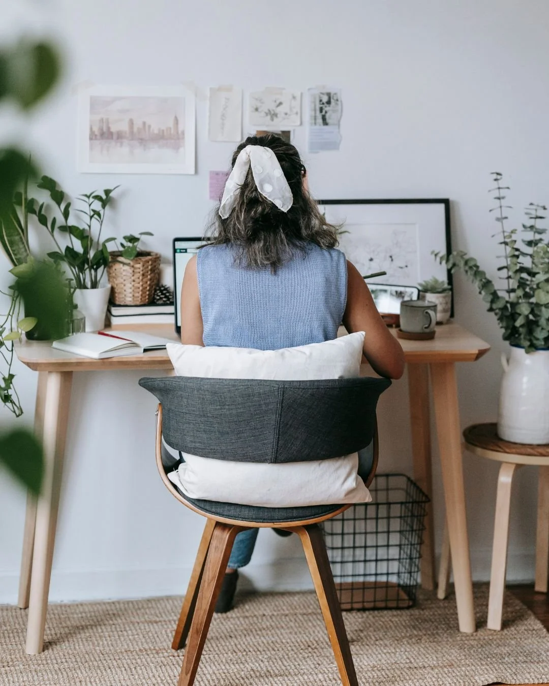 Woman working at a home office desk surrounded by plants, symbolizing reflection and growth in developing leadership strengths