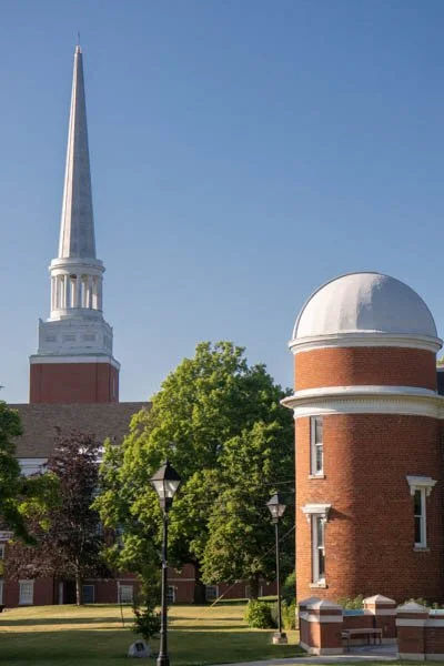 Church steeple and a observatory, surrounded by trees and lampposts