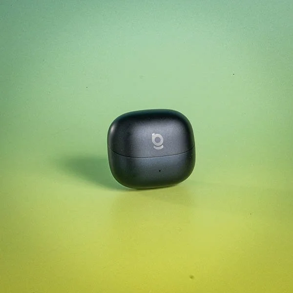 Black wireless earbuds case with a lowercase 'b' logo on a light green background.