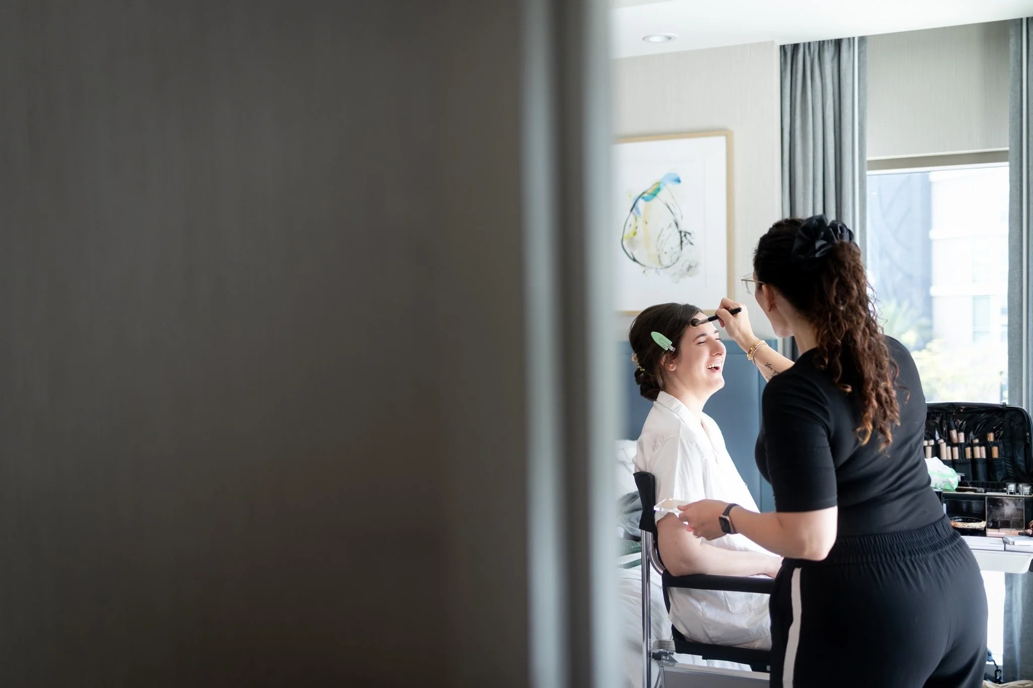 makeup artist applying makeup to bride laughing relaxed happy