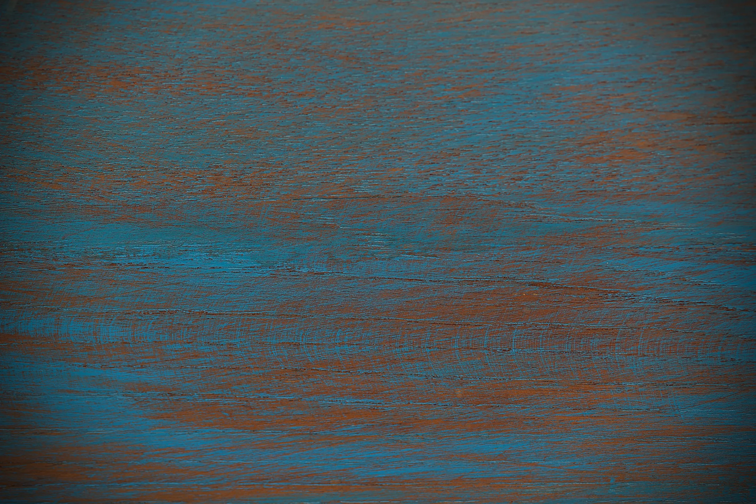 Close-up of a wooden surface painted in a mix of blue and orange colors.