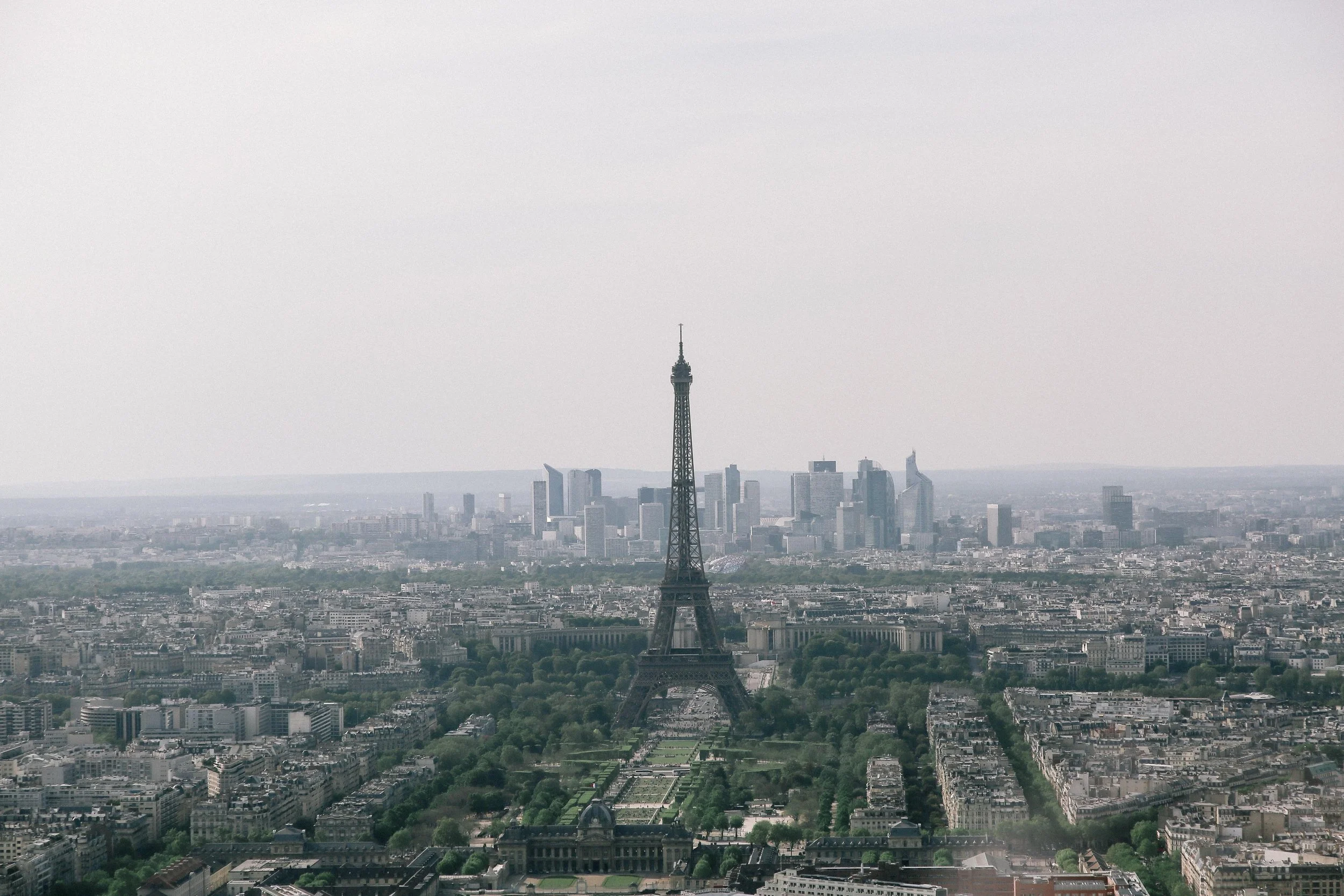 Aerial view of the Eiffel Tower with Paris cityscape in the background, overcast sky