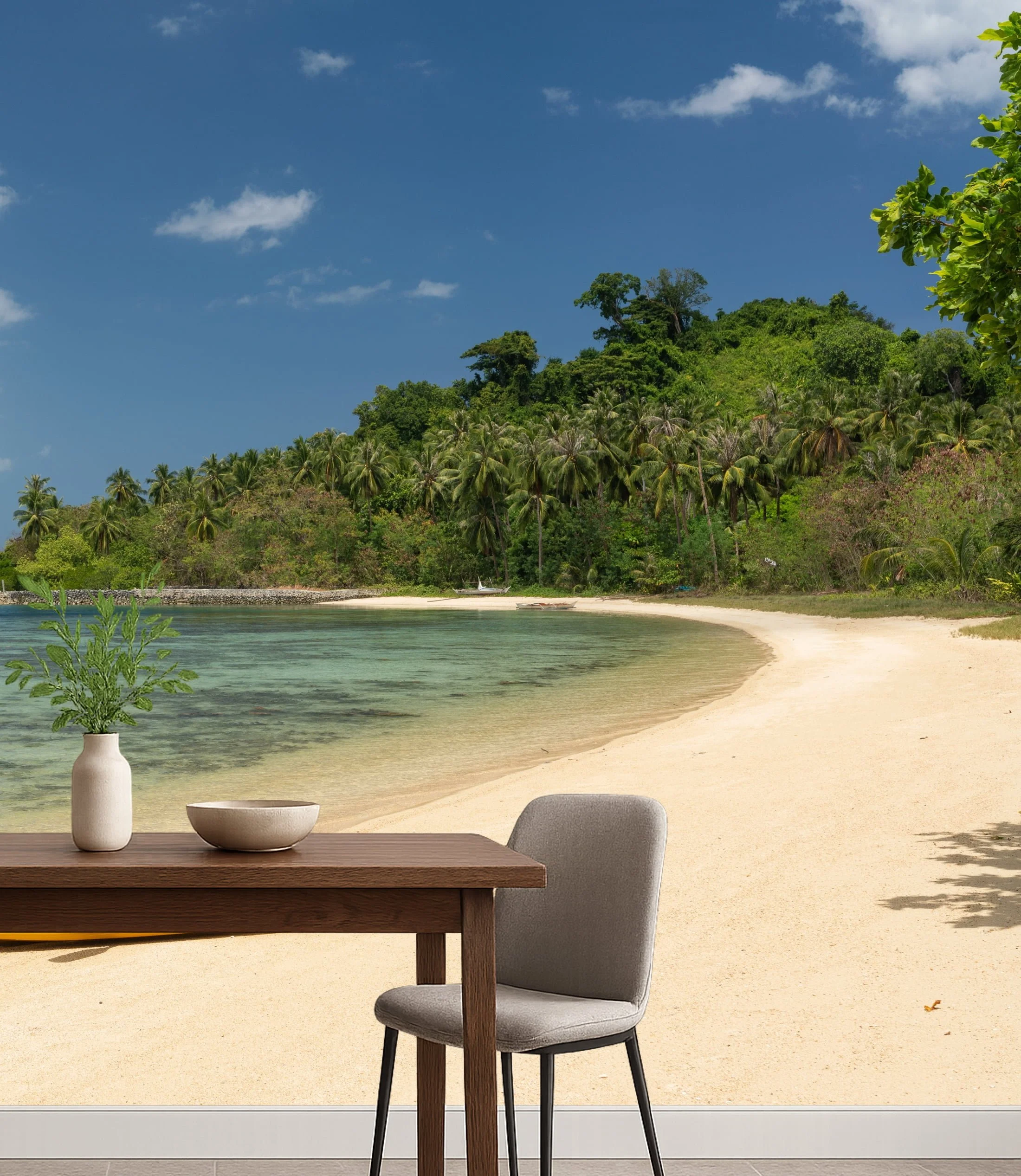 Beachfront dining room wall mural wallpaper with tropical palm trees, blue sky and sand viewed from outdoor table and chairs – Pop Papel panoramic coastal wallcovering