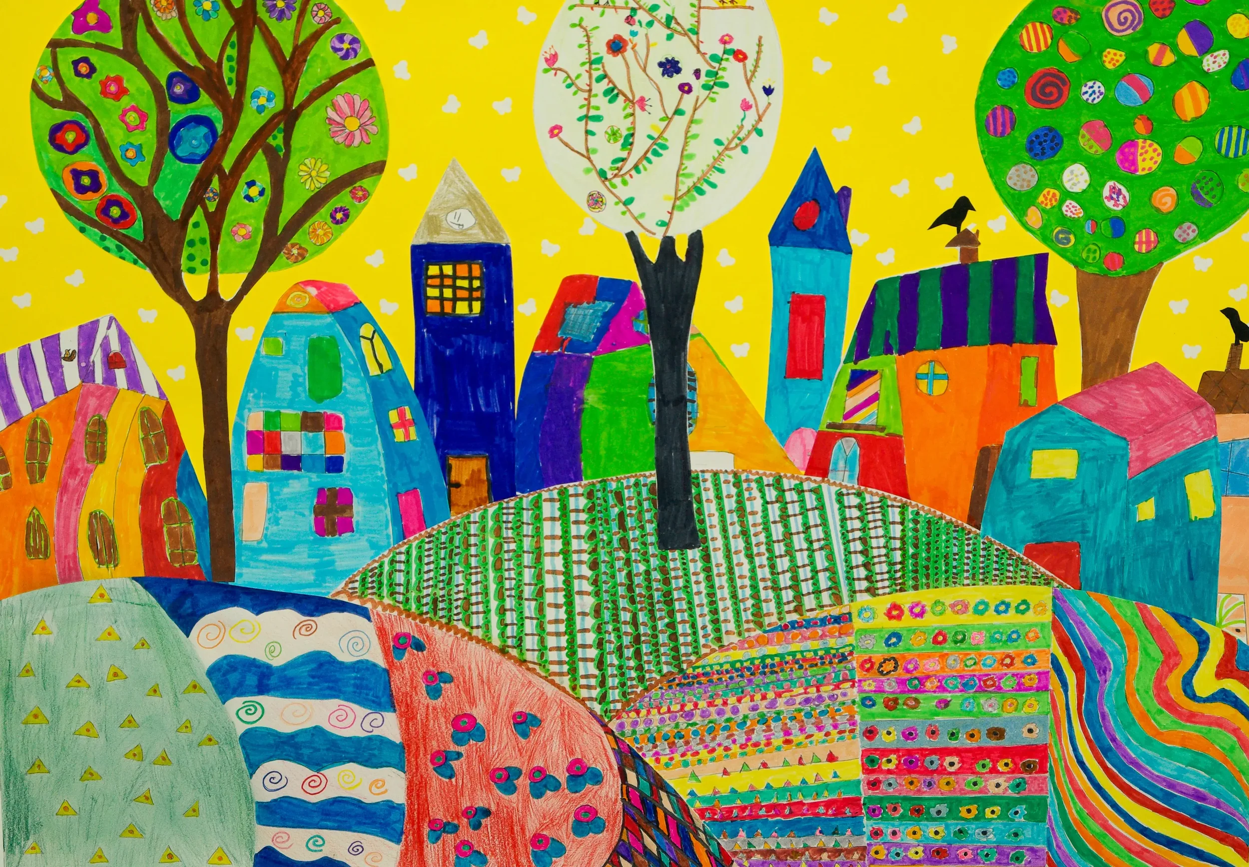 Colorful, childlike drawing of a hillside with patterned fields, several vibrant houses, and three large trees with colorful, patterned canopies against a yellow sky.