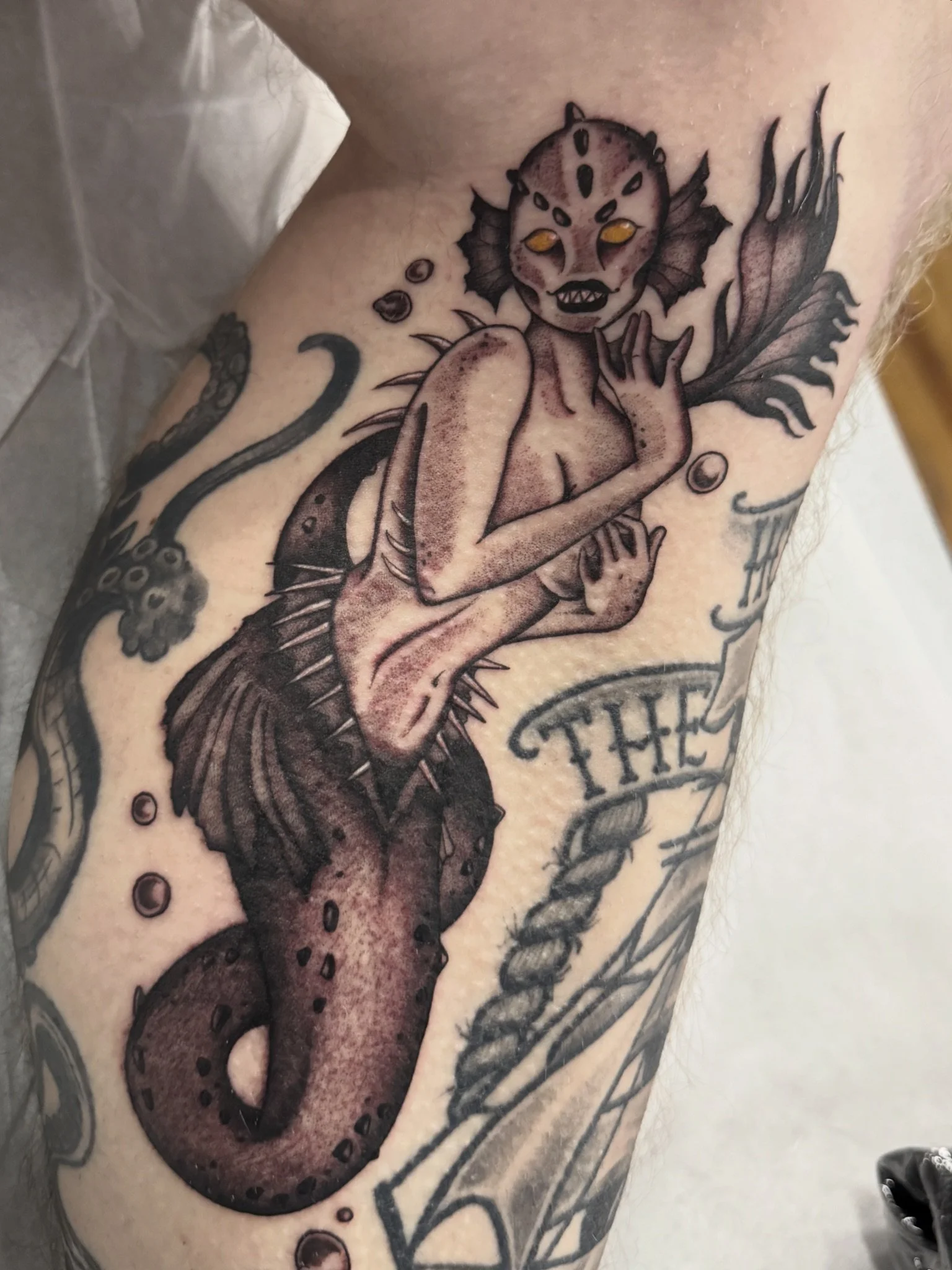 Tattoo of a Fiji mermaid with fins and a tail.
