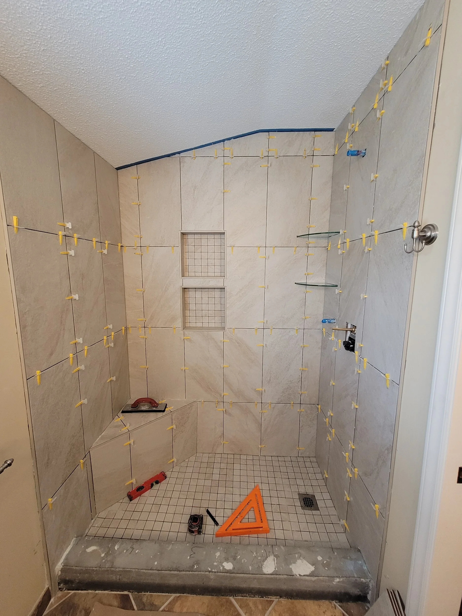 Custom tile shower installation in progress showing wall tile and built-in shower niche