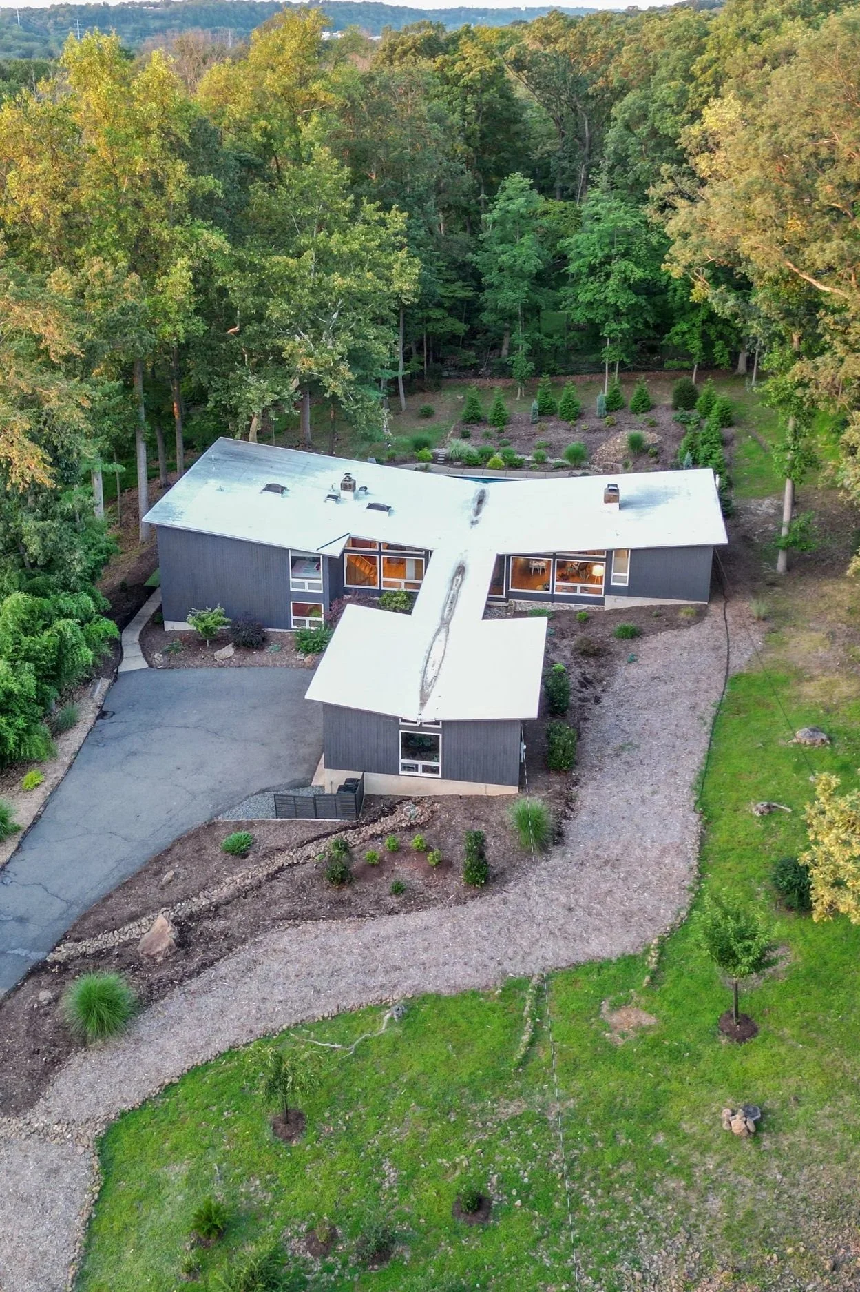 Aerial view of mid-century modern filming location in Watchung, NJ, surrounded by wooded landscape with driveway access and naturalistic grounds.