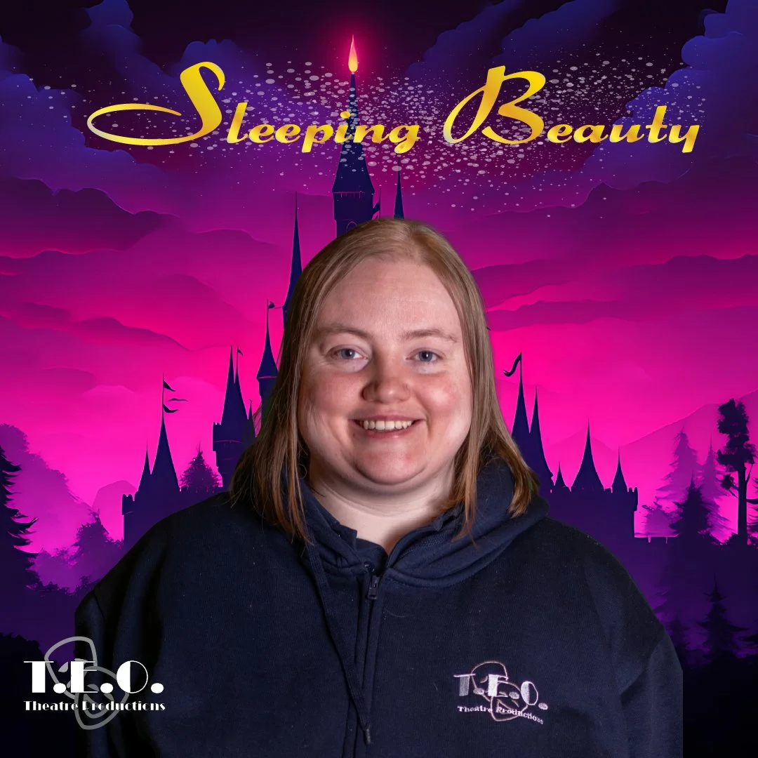 A woman with shoulder-length red hair smiling, wearing a black jacket with a theater production logo. Behind her is a purple and pink fairy-tale castle silhouette with the text 'Sleeping Beauty' in gold, and a night sky with stars and clouds.