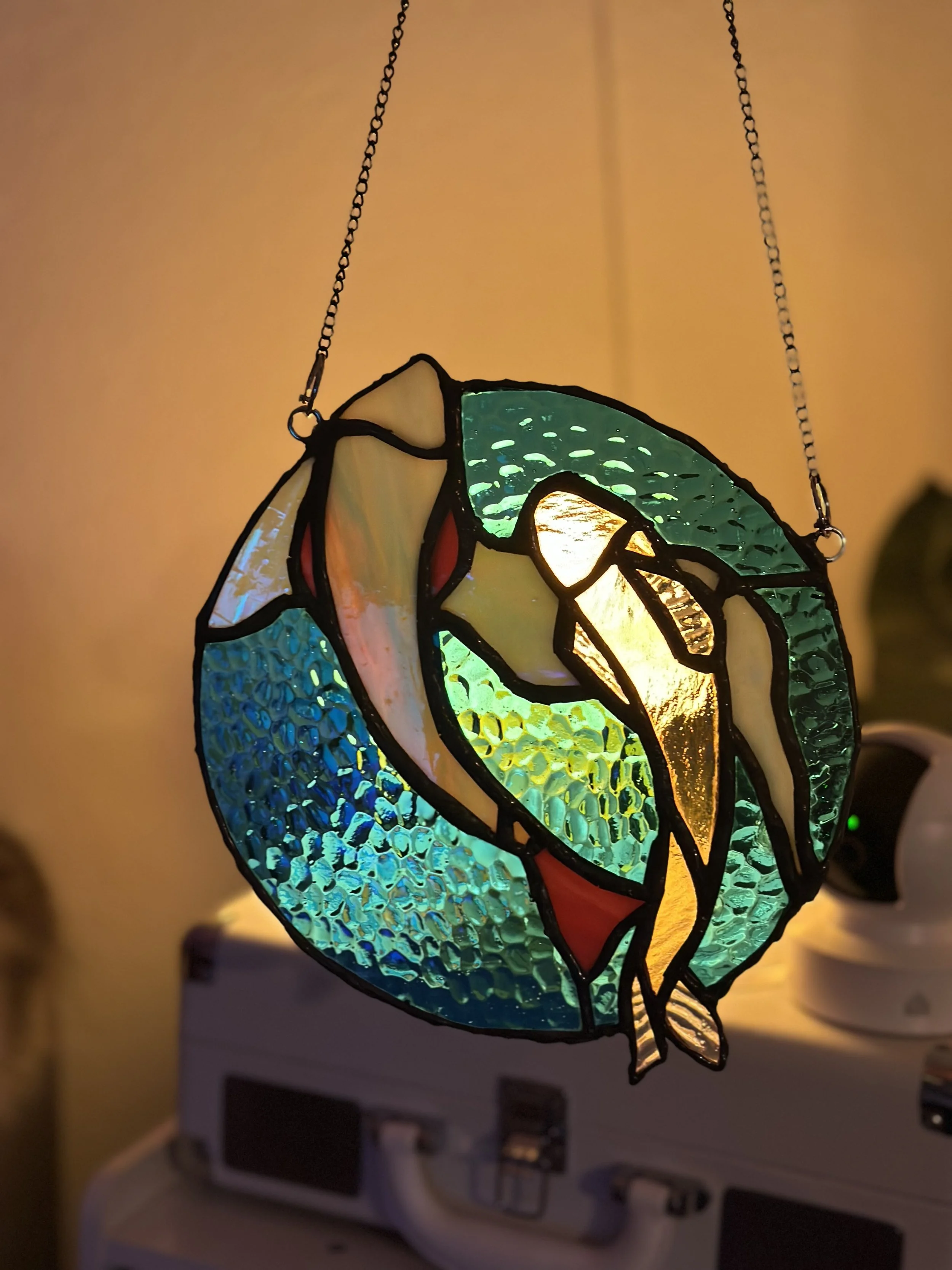 Stained glass hanging lamp with a heron design against a warm background.