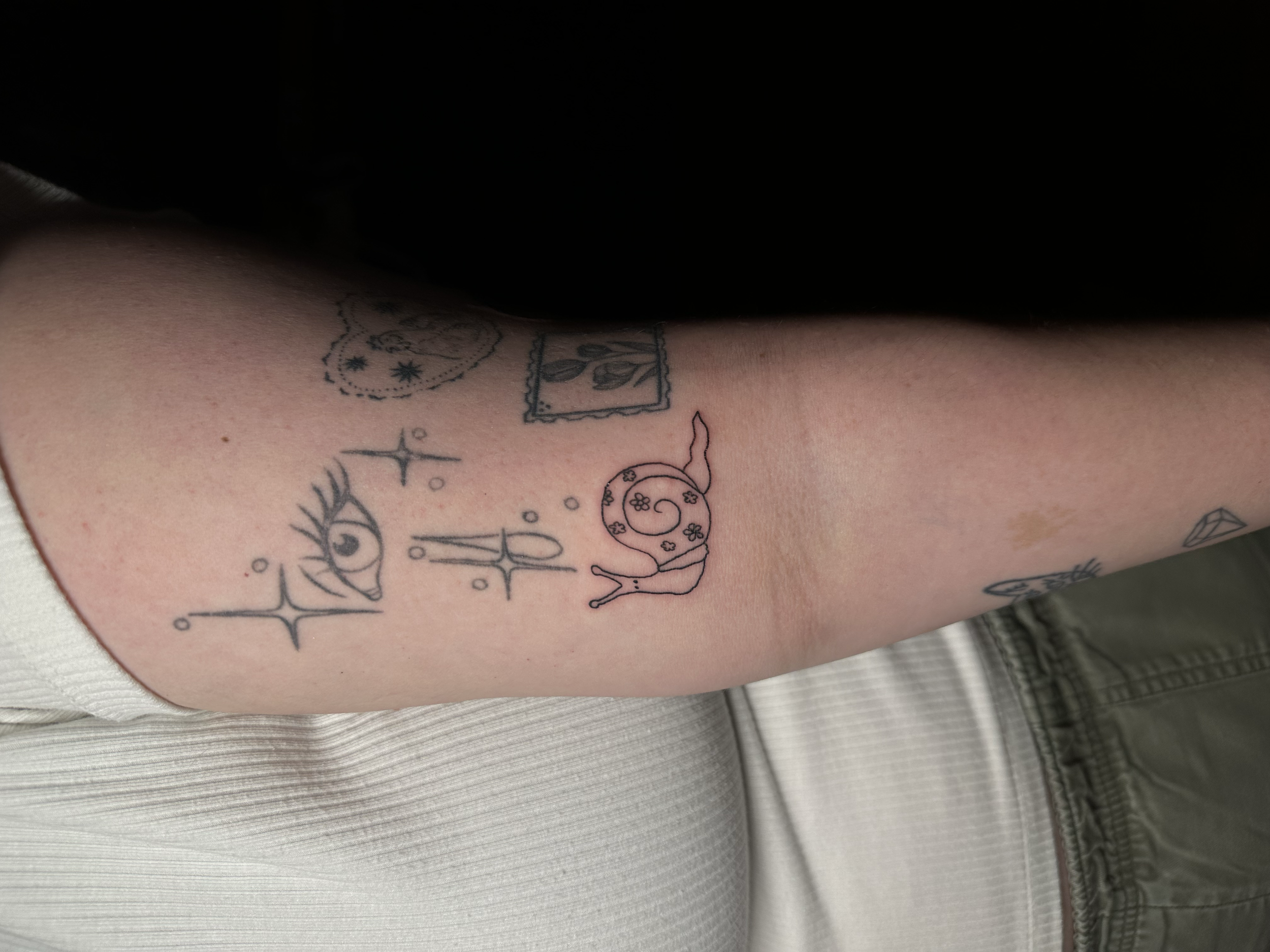 Tattoo of an eye with long eyelashes, a star, and small circles on the upper arm.