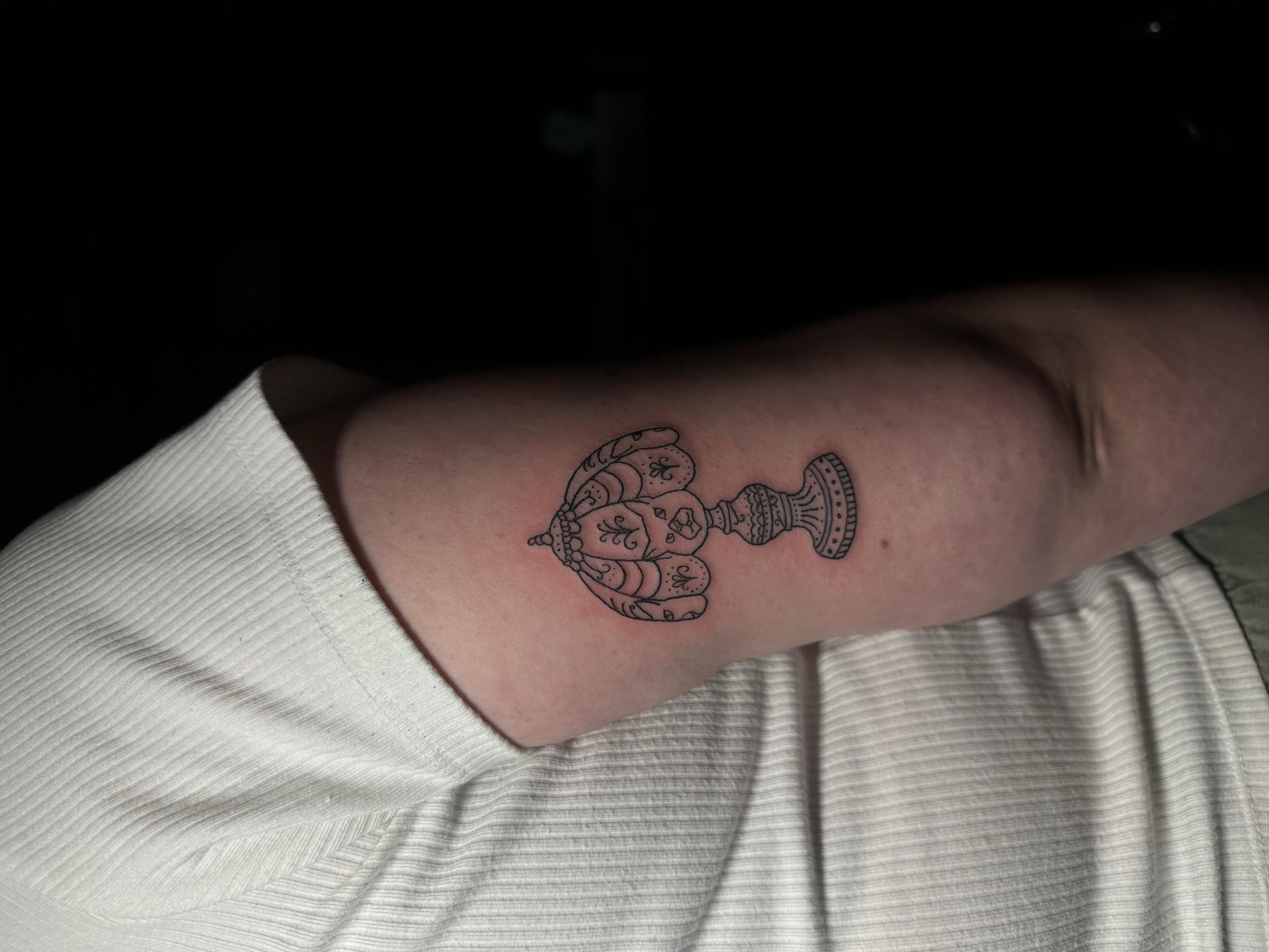 A tattoo of a decorative lamp on a person's upper arm.