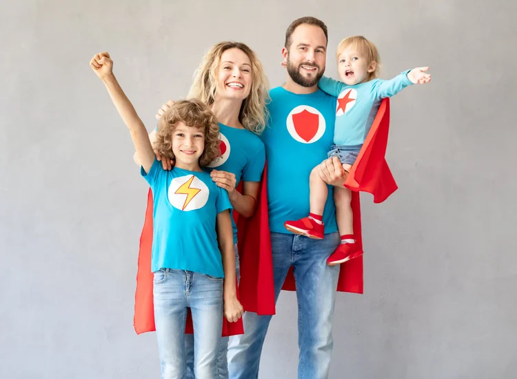 Family wearing playful superhero costumes at home