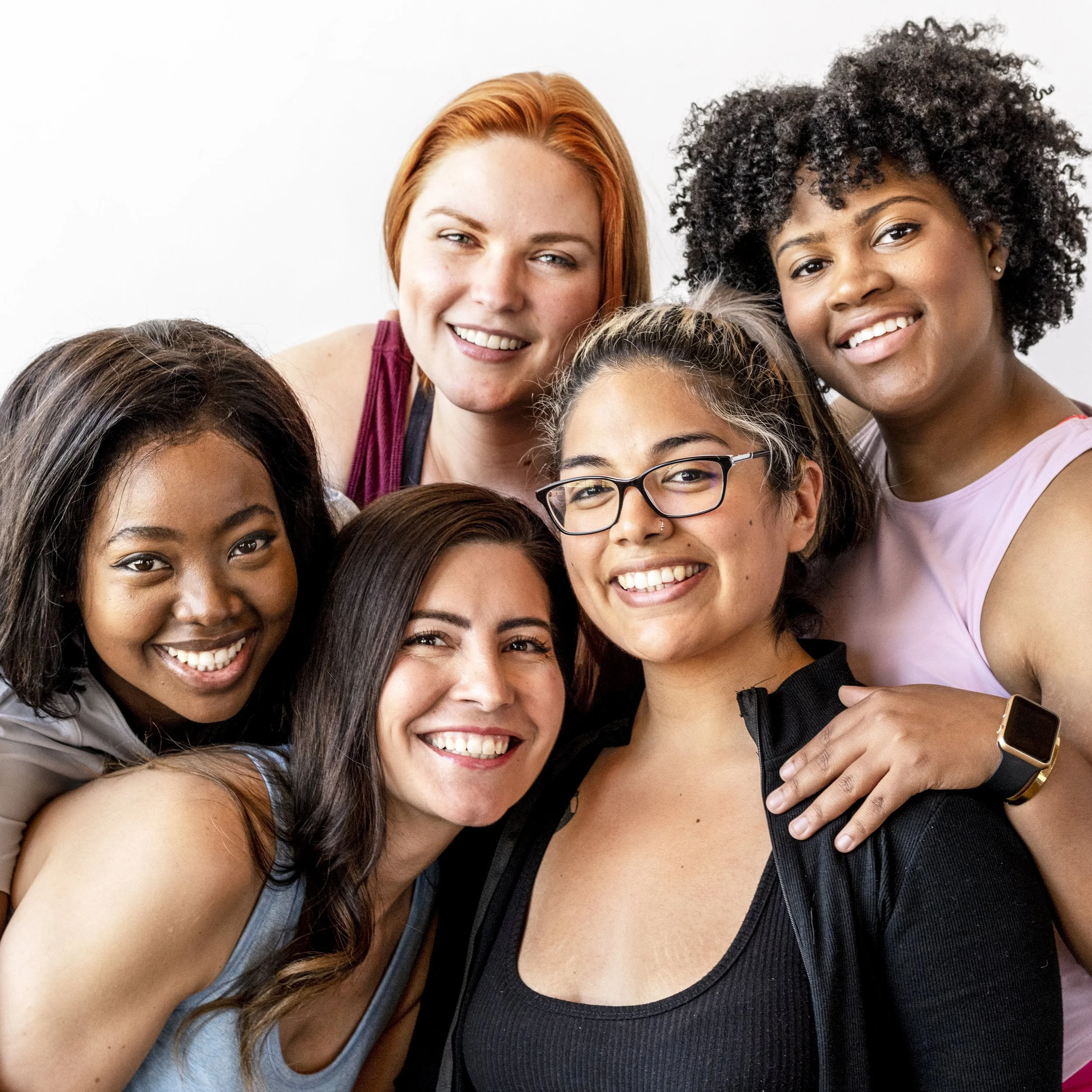Group of six diverse women smiling together indoors.